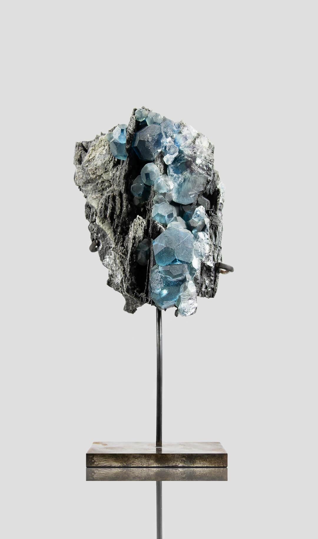 Raros racimos de cristales isométricos de fluorita azul encapsulan una estética sorprendente, mostrando intrincados detalles de forma cúbica isométrica con un contraste sin fisuras entre los cristales azules y el lecho rocoso antracítico de cristal