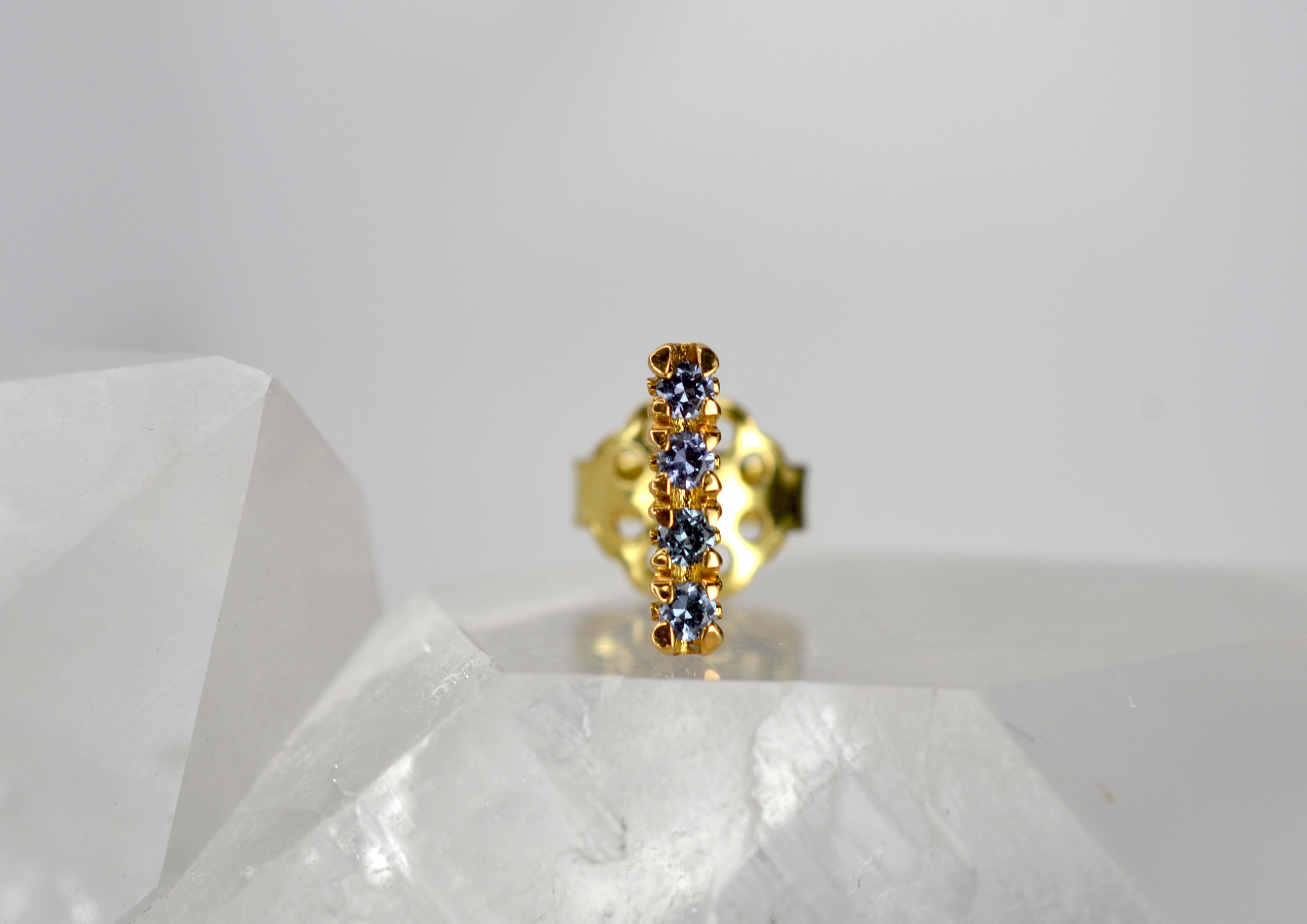 This single earring stud is part of our Blossom Collection of mix and match pieces. This marvellous greenish-blue colour change garnets are set on an 18k gold blossom flower collet to be worn alongside your favourite pair of earrings, our blossom