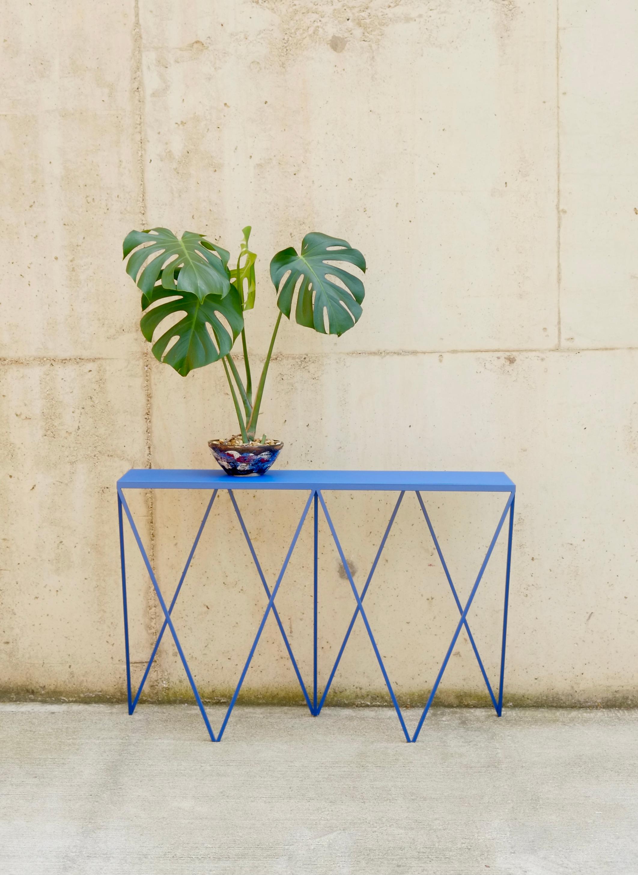 A bold blue Giraffe Console Table made with a powder coated steel frame and a color matched linoleum table top. The top is made out of environmentally friendly linoleum. The linoleum top is produced from a very finely ground linoleum granulate
