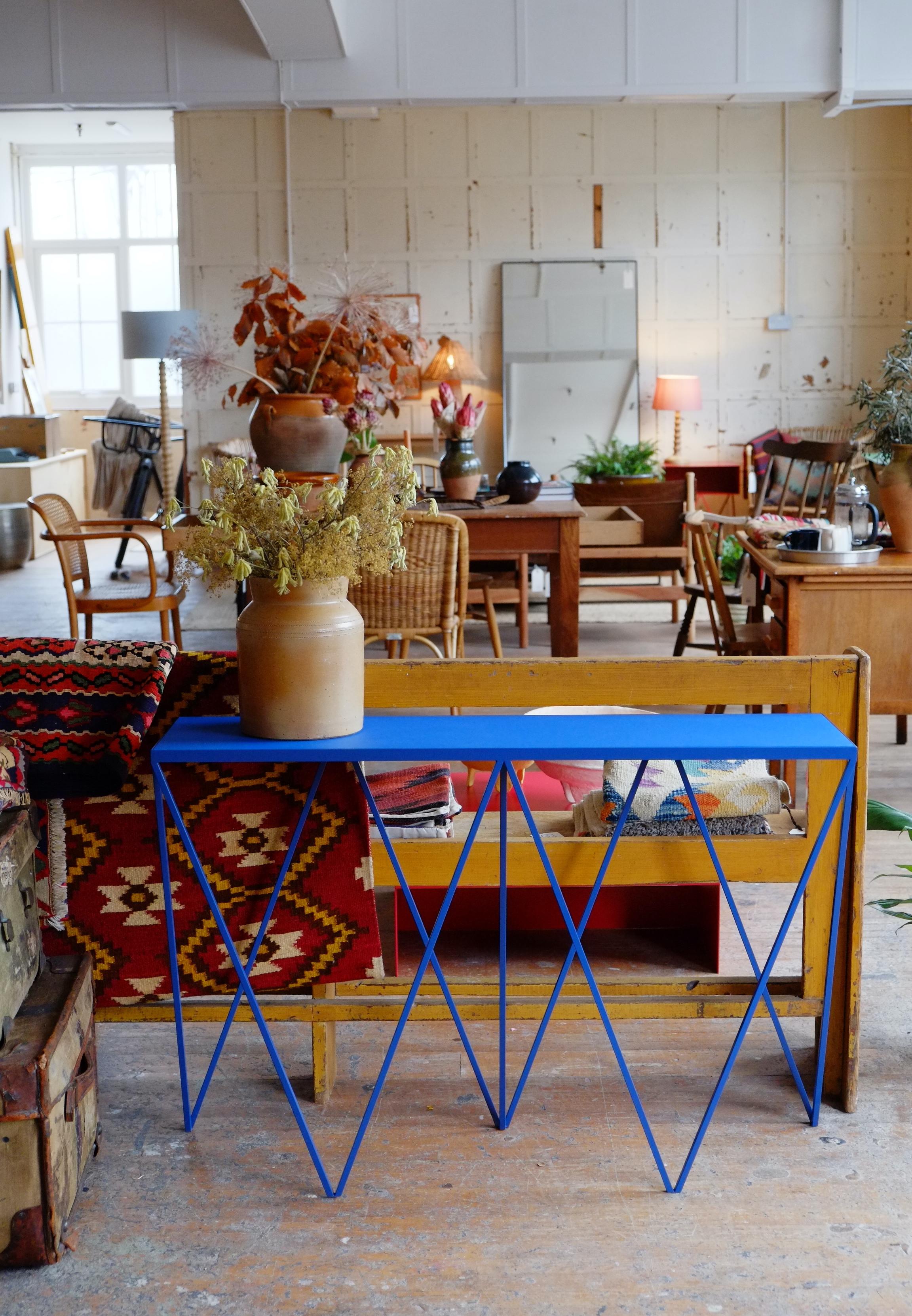 A bold blue Giraffe Console Table made with a powder coated steel frame and a color matched linoleum table top. The top is made out of environmentally friendly linoleum. The linoleum top is produced from a very finely ground linoleum granulate
