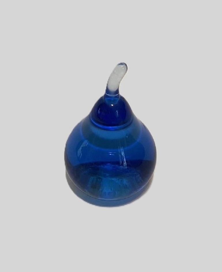 A lovely blue glass apple paperweight. Expertly crafted in a rich, translucent blue glass, this charming piece is formed in the shape of a stylized apple with a smooth, rounded body and a clear glass stem. The vibrant color catches and reflects the