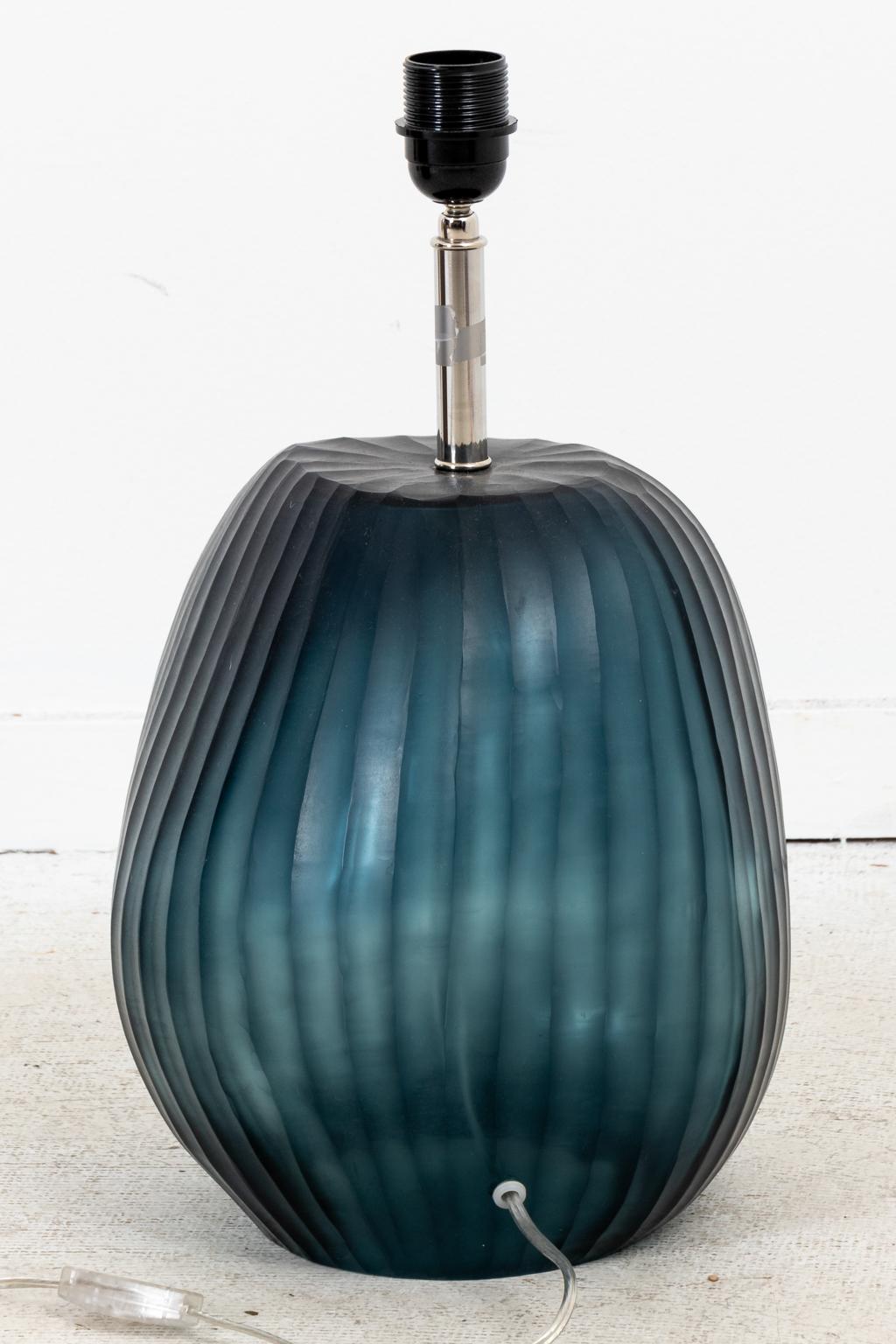 Contemporary hand blown Ocean blue glass table lamp with sanded surface in irregular striated pattern with grey fabric shade. The body measures 10.00 inches diameter by 12.00 inches height. The overall height of the piece is 27.25 inches. Shades not