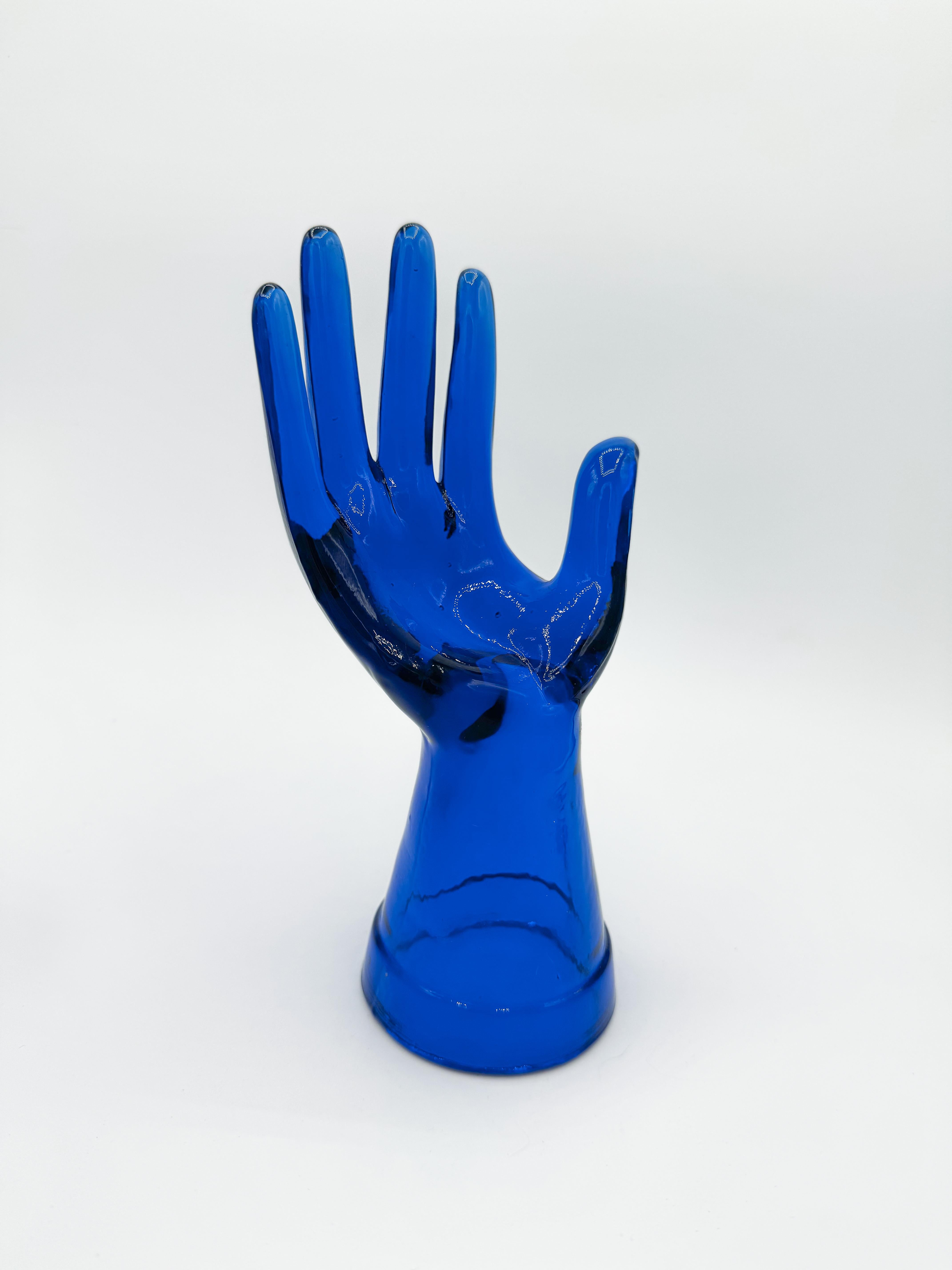 Mano de cristal azul vintage de los años 60. Perfecta para exhibir anillos, cadenas, relojes, pañuelos y otros accesorios de moda, esta pieza única añade un toque de interés visual a cualquier rincón de tu espacio.

Fabricada con cristal azul grueso