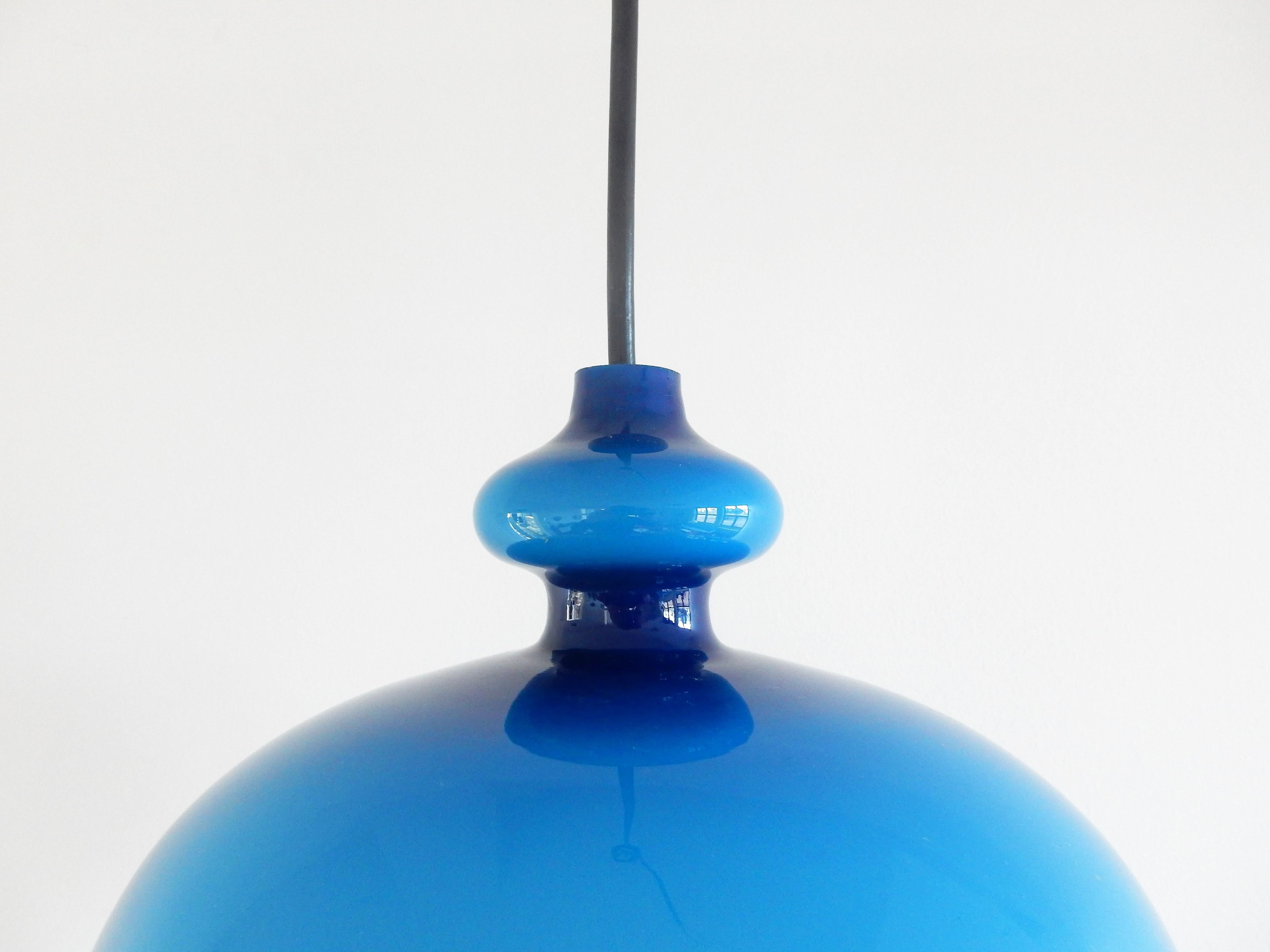 This beautiful round shaped glass pendant lamp was designed by Hans Agne Jakobsson for Svera in the 1960's. It has a bright blue colored glass shade with an opaline inside for a beautiful softened light. This lamp is in a good condition with a small