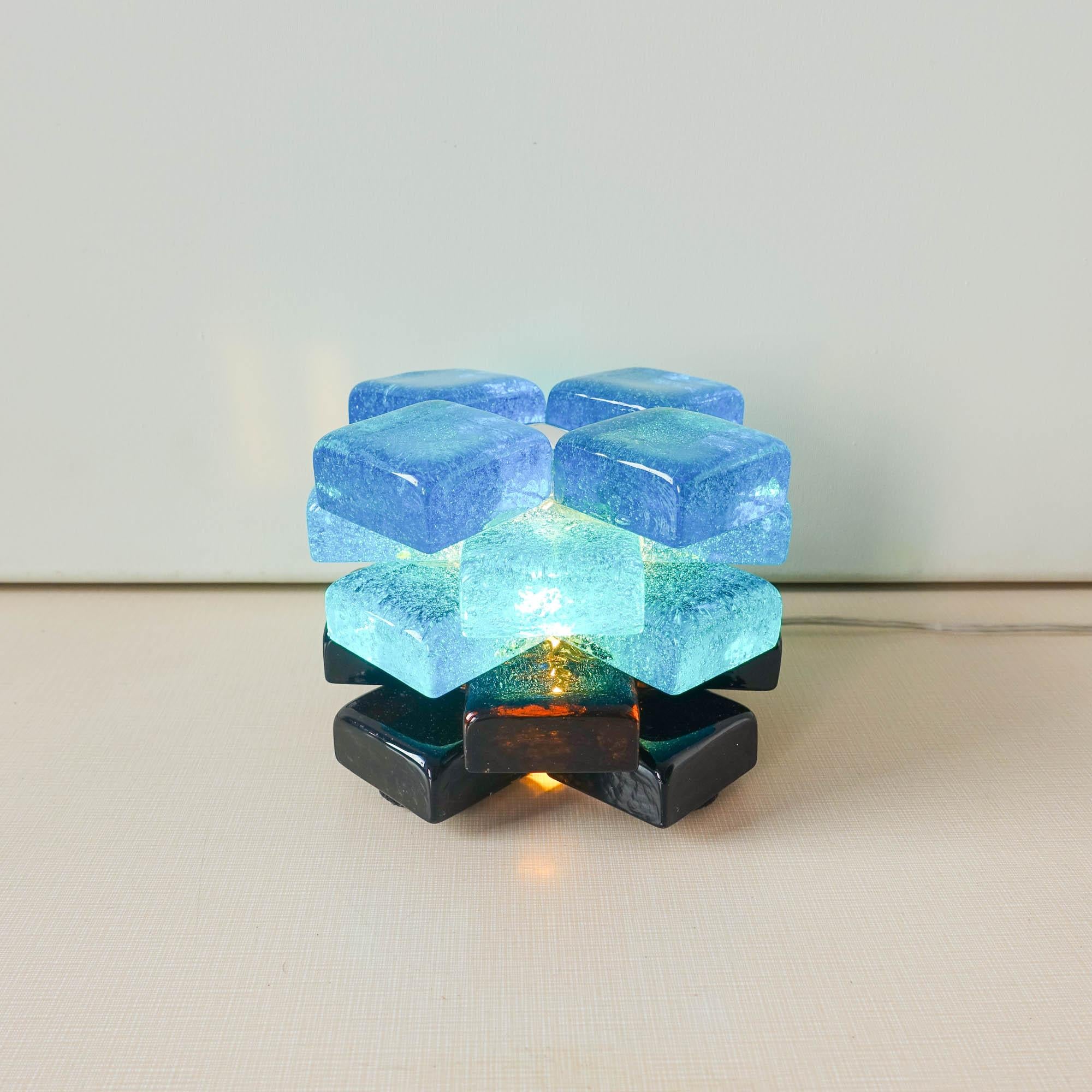 This table lamp was designed by Albano Poli, for Poliarte, in Italy, during the 1970's. It is composed by 20 murano glass cubes, 12 blue and 8 black. An iconic lamp that diffuses a very beautiful light. In original and very good condition.