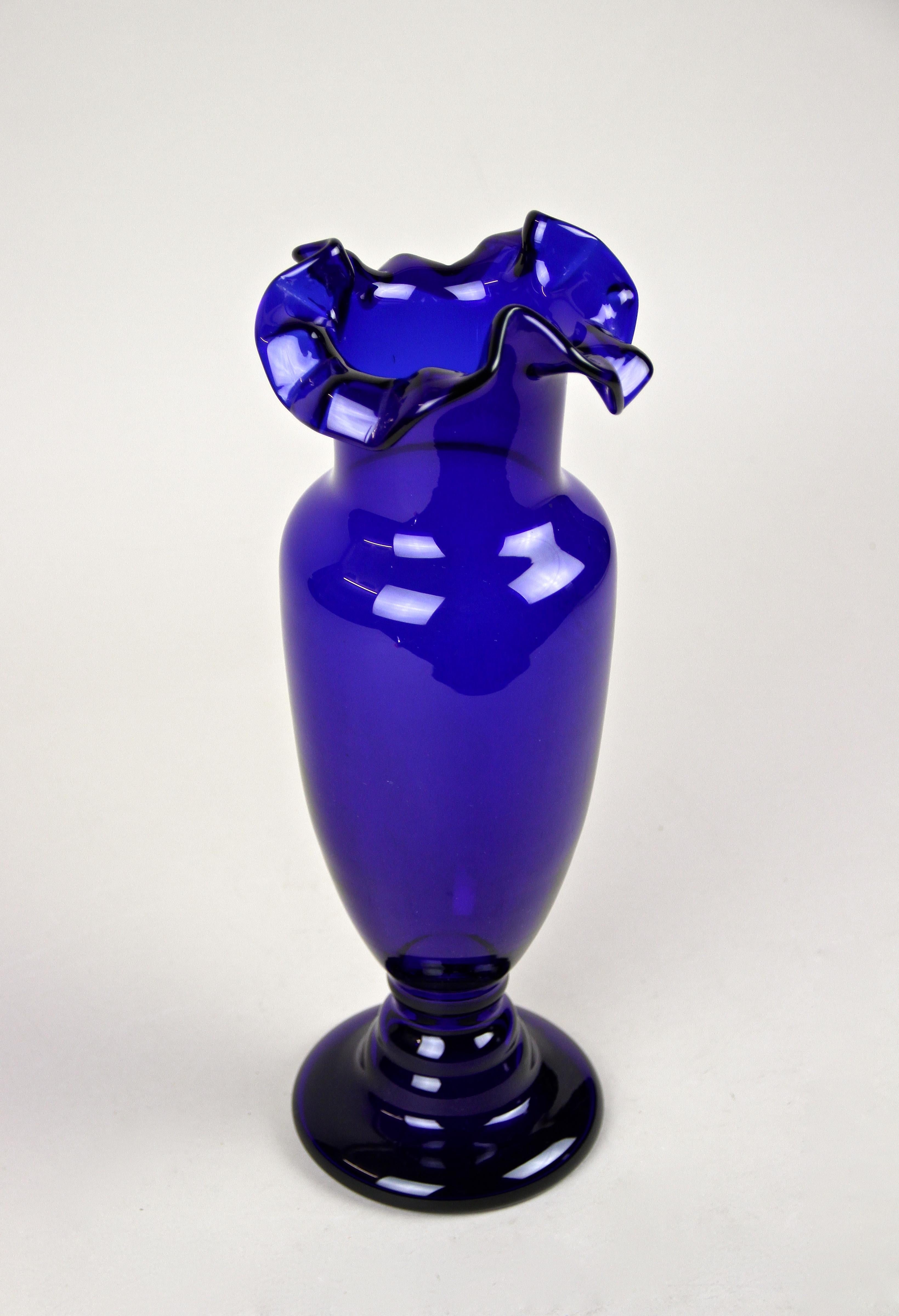 Faszinierende blaue Glasvase aus dem frühen 20. Jahrhundert aus der Jugendstilzeit in Österreich. Die um 1900 entworfene Glasvase zeigt einen bauchigen, mundgeblasenen dunkelblauen Körper und besticht durch ihren schön gebogenen, gerüschten