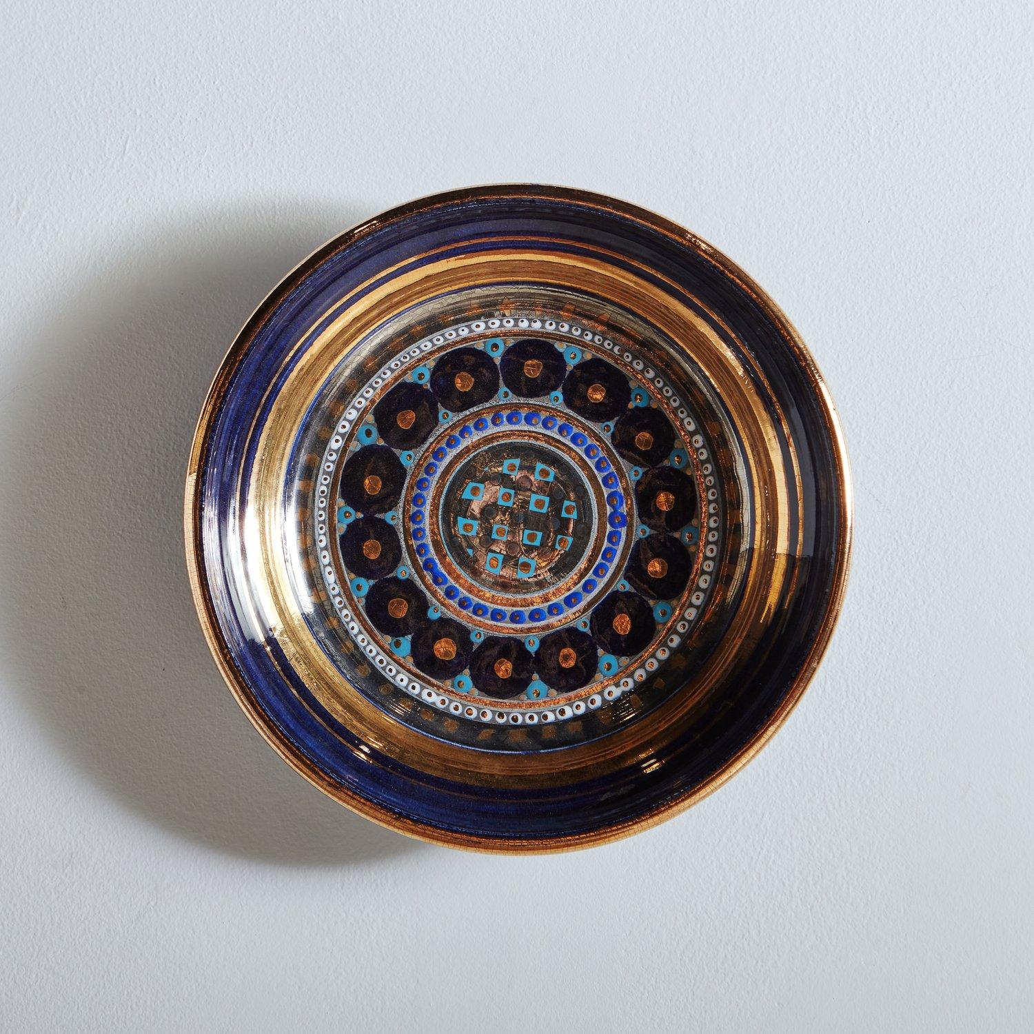 A mid-century glazed ceramic bowl by French ceramicist Georges Pelletier. This piece has a beautiful range of blue, black and gold hues in a circular geometric pattern. Signature on bottom. This piece can be displayed on a tabletop or hung on the