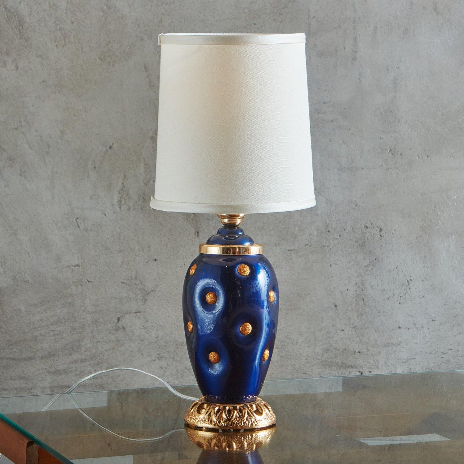 A vintage Italian table lamp with a striking royal blue glazed porcelain body and gold metal medallion detailing. It stands on an ornate gold metal base and has a new cream fabric shade. Unmarked. Sourced in Italy, 1980s. 

4.5”Dia x 14”H to Socket;