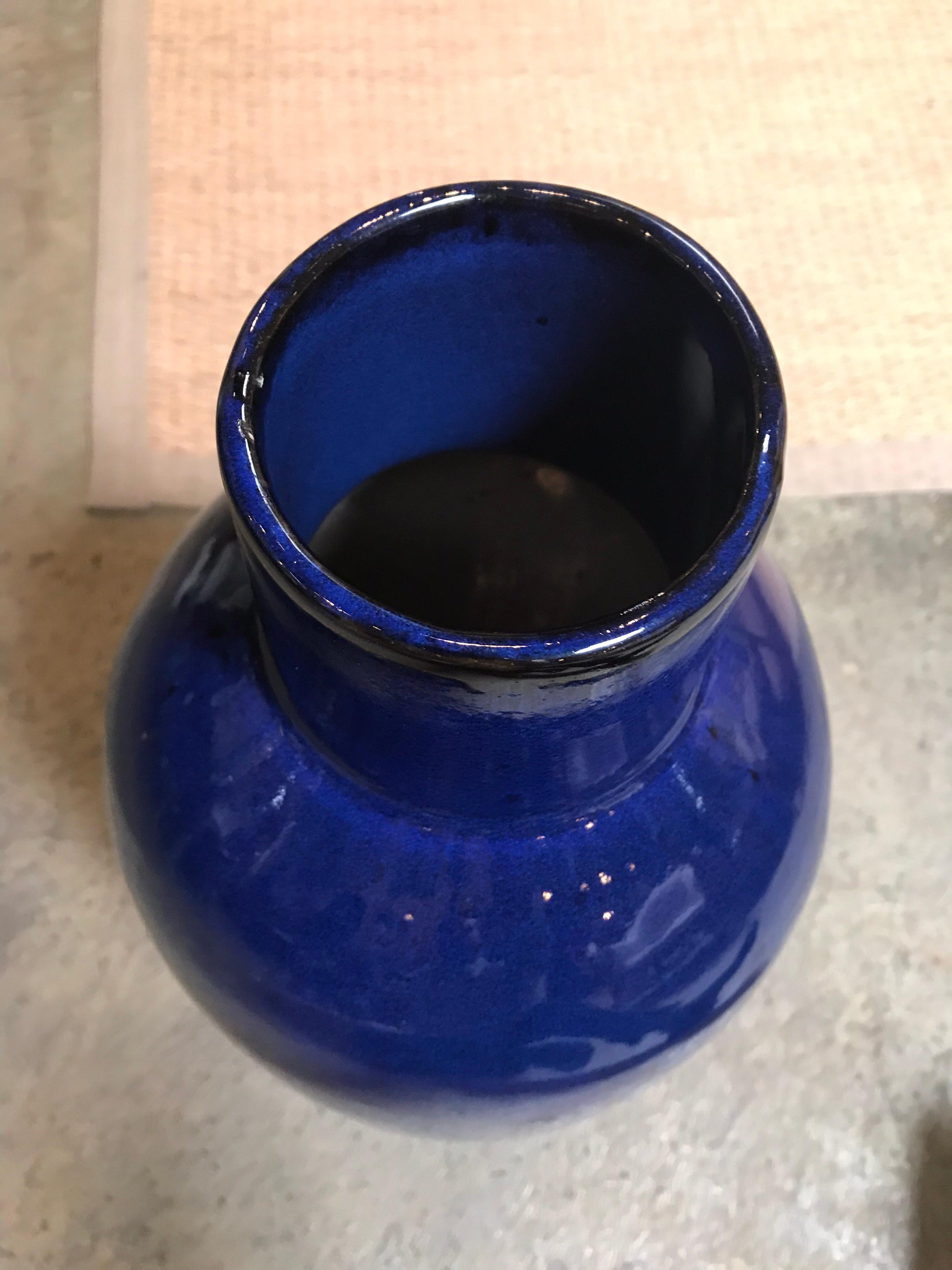 This taller, dark blue gourd vase is handmade and has a ceramic glaze.