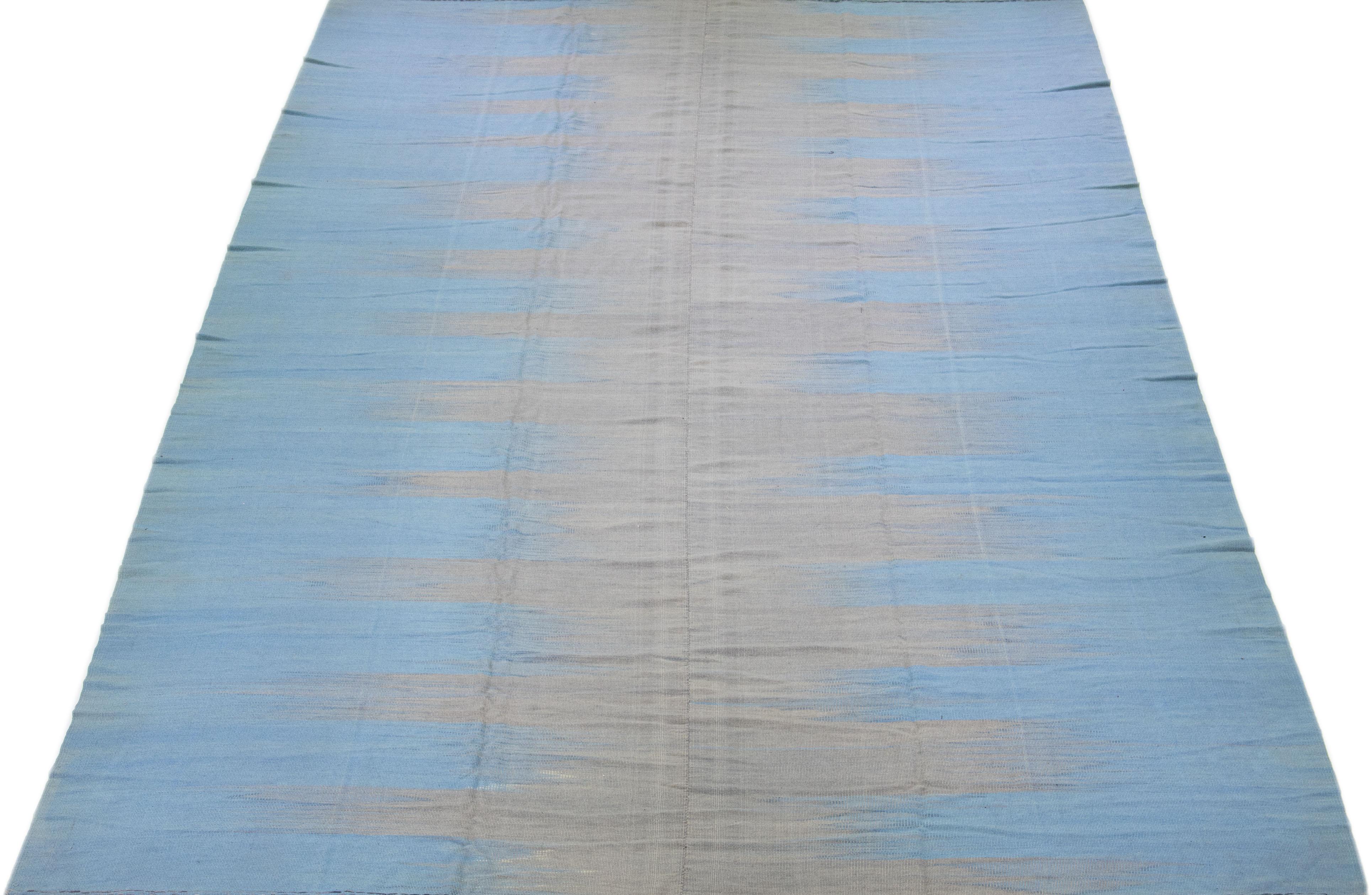 Schöner moderner flachgewebter Kilim-Wollteppich in einem blauen Farbfeld mit grauen Akzenten in einem herrlichen abstrakten Design.

Dieser Teppich misst 11'9