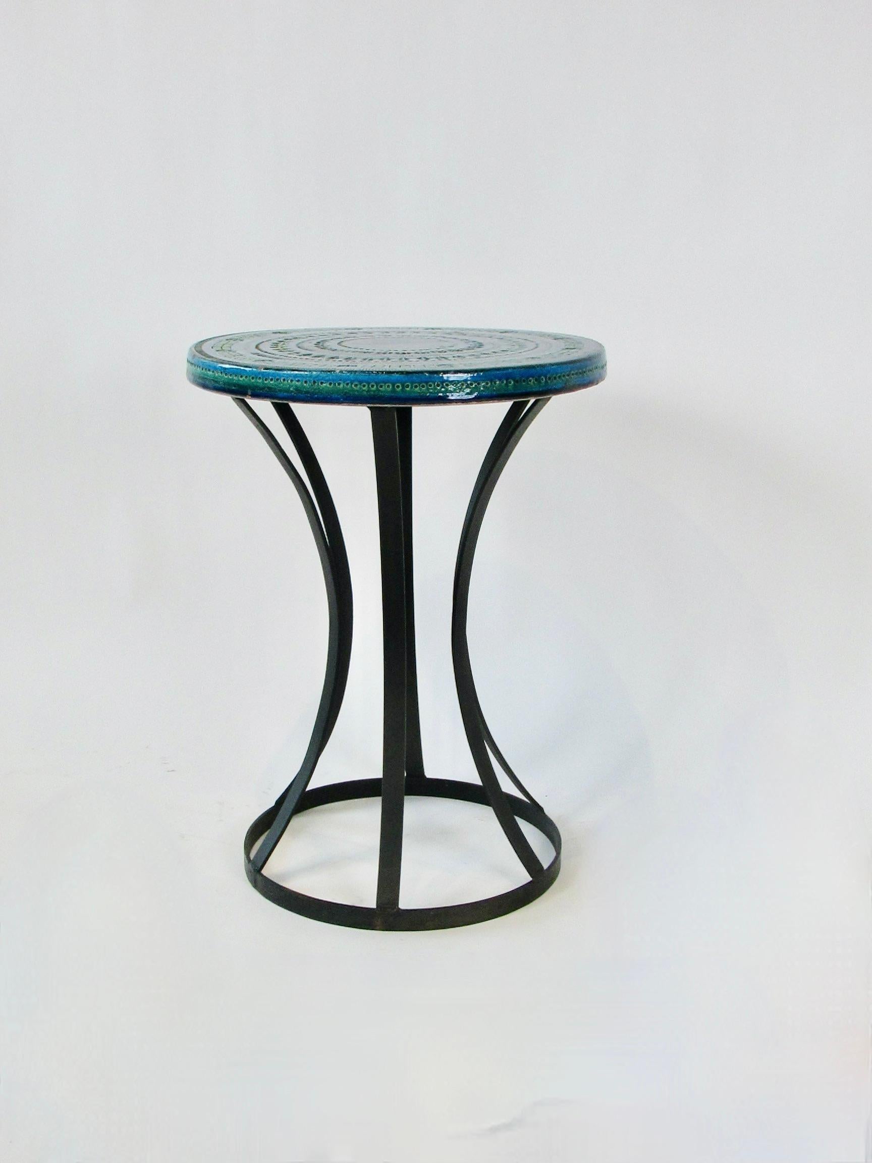 Beautifully blended colors of blues and green fired on Aldo Londi designed pottery table. Pattern is incised into table top. Top sits on flat band wrought iron hourglass base. Imported from Italy by Raymor co.