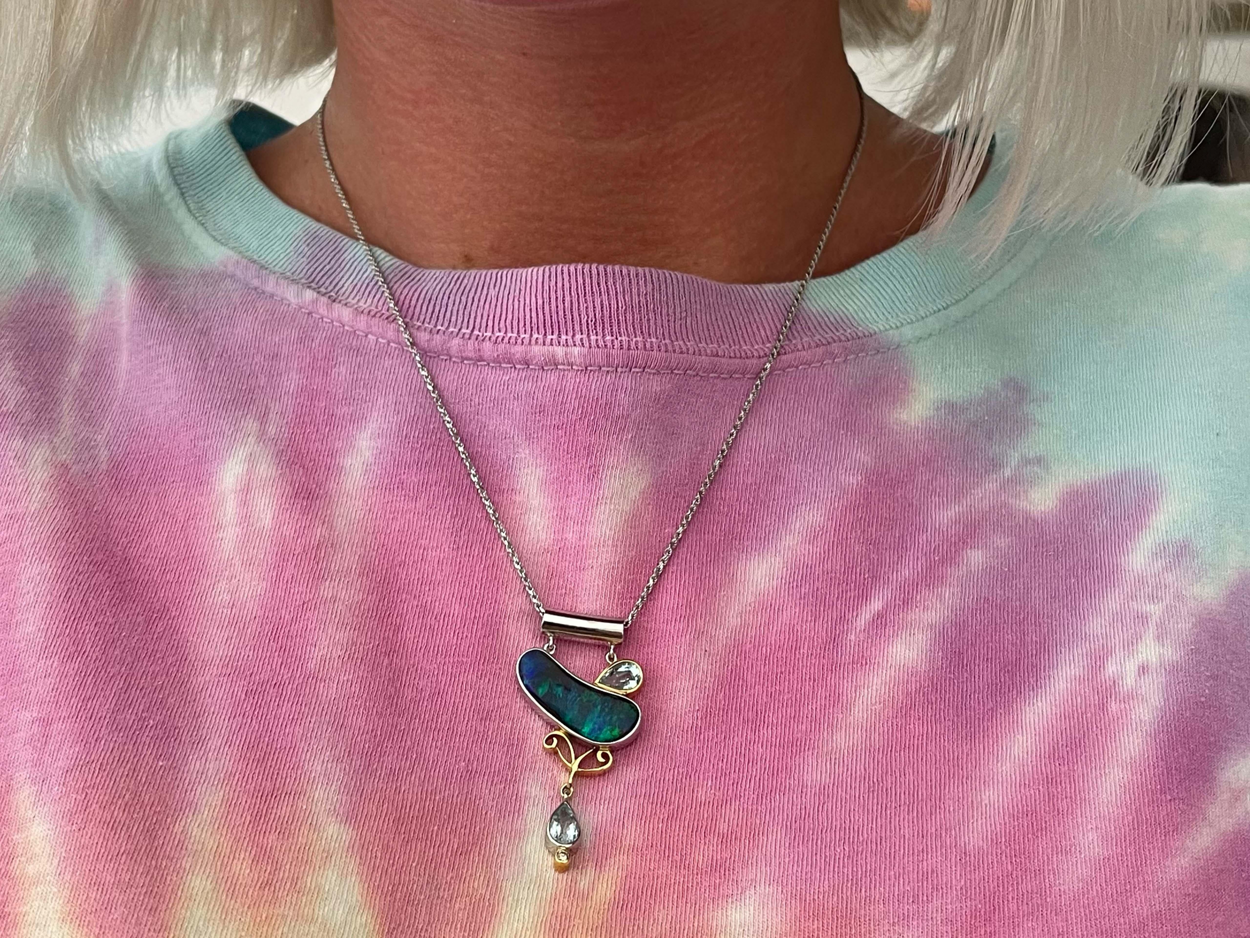This unique piece of jewelry is one-of-a-kind. At its center is a stunning blue green opal, resembling the Northern lights of Alaska, a truly rare phenomenon, this opal is much the same in its rare stunning color play of deep blue and electric green