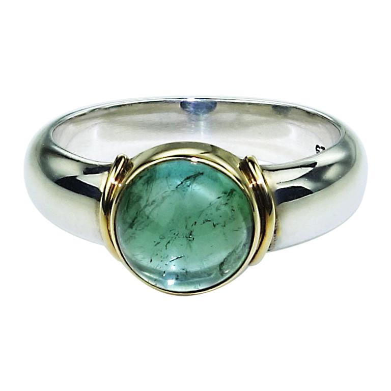 Gorgeous ring of Sterling Silver with 18K Gold Accents featuring a bright blue-green round Tourmaline cabochon.  The Tourmaline is a round cabochon with typical inclusions which add to the sparkle. Steven Battelle designed ring.  The sizable 7 ring