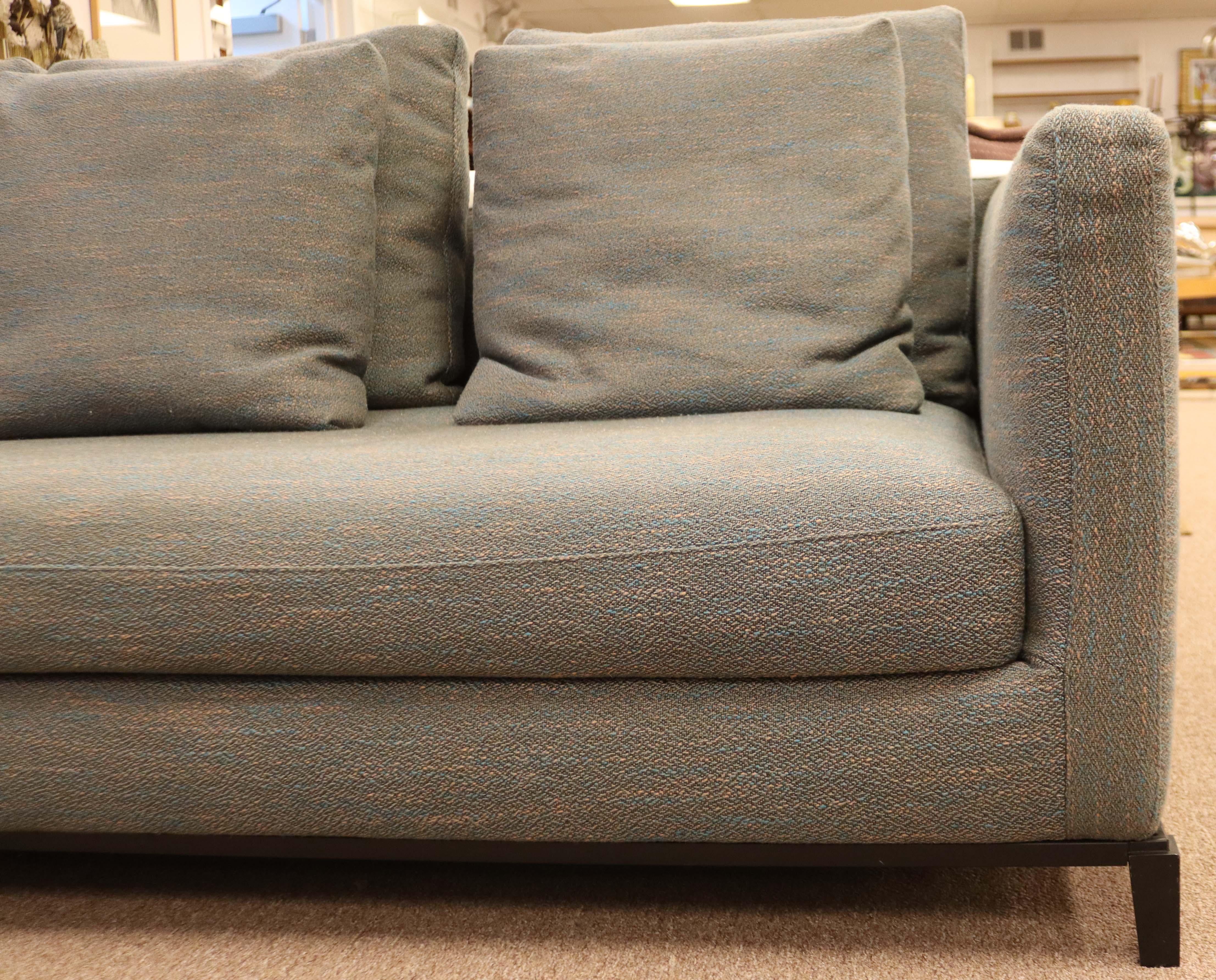 Up for sale is a sophisticated, full size sofa in a blue and grey textured upholstery in very good condition. The exposed steel base is finished in a dark stain and adds a clean line detail to the piece. Also included are six removable back cushions