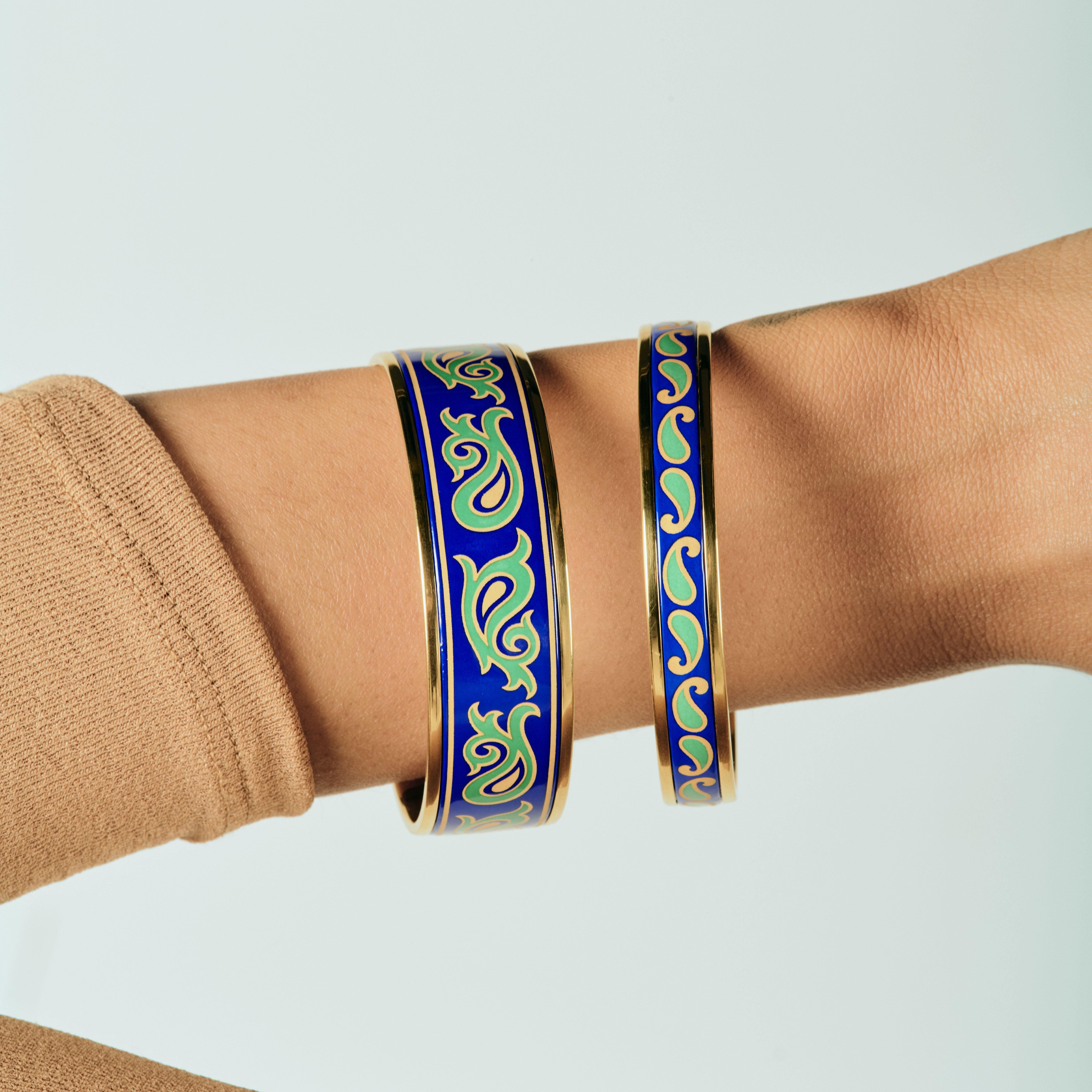Introducing the Eternity Bangle. Elevate your style with our exquisite 18k gold-plated stainless steel bangle. Hand-painted with genuine fire enamel in vivid colors that will last forever, this luxurious piece is designed to make a statement.