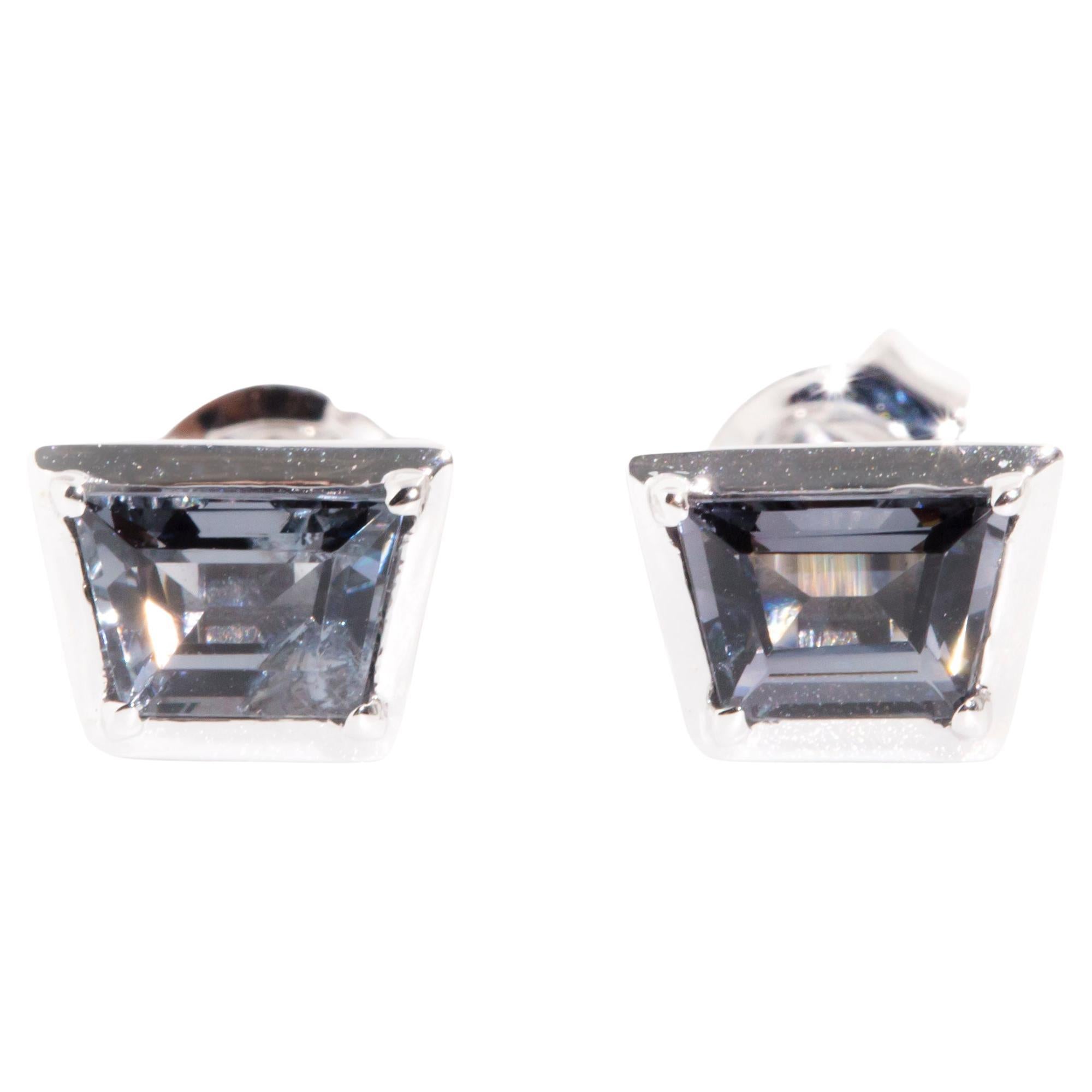 Crafted in 9 carat white gold, these alluring contemporary stud style earrings each feature a wonderous bright blue grey trapezoid cut spinel sitting in a gorgeous tapered bezel setting. We named these petite studs The Lucie Earrings. She fits