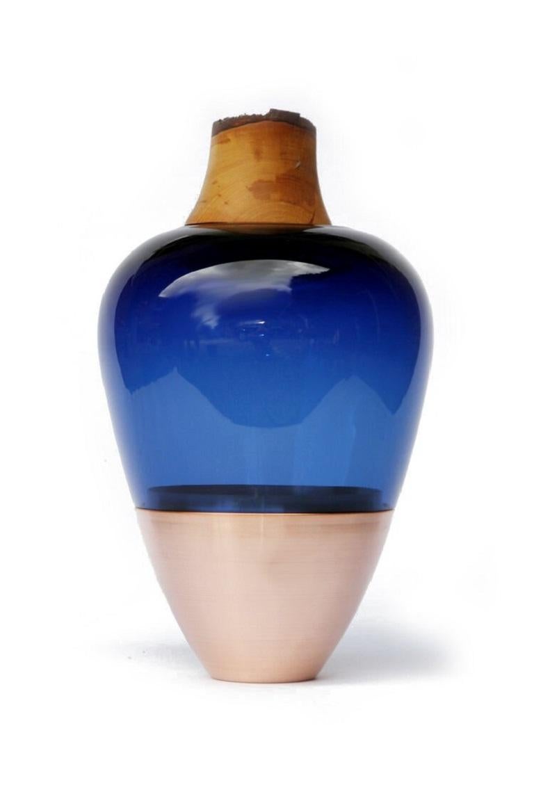 Blue India vessel I, Pia Wüstenberg
Dimensions: D 20 x H 38
Materials: glass, wood, copper

Handmade in Europe, by individual craftsmen: handblown glass (Czech Republic), hand spun metal, (England), hand turned wood (Finland). The materials then