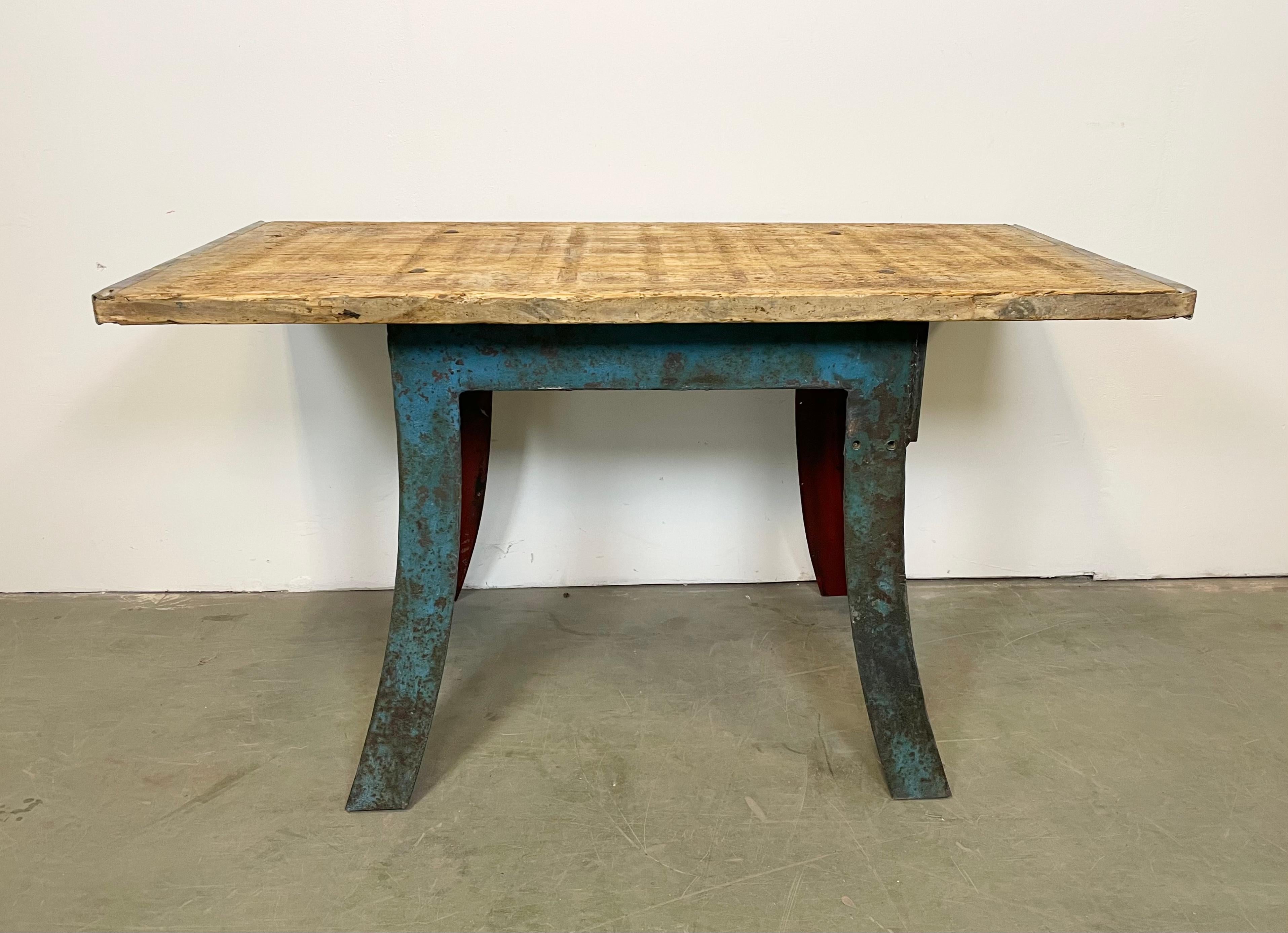 Industrial dining table from the 1960s. It features a blue iron table base and a solid old wooden plate with very nice patina. The weight of the table is 80 kg.