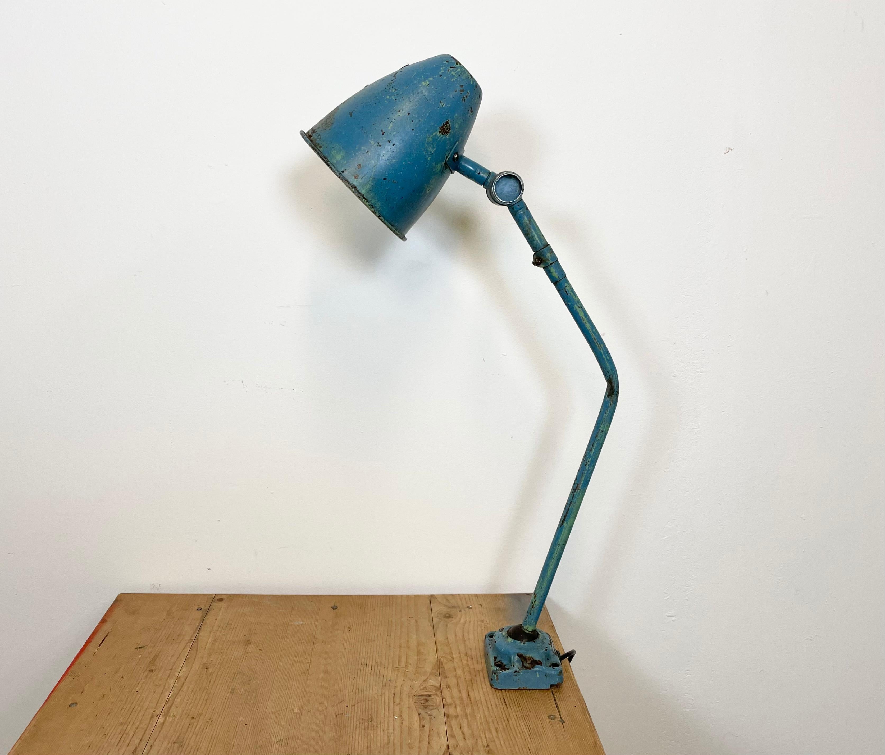 This blue industrial style iron table lamp was made in former Czechoslovakia during the 1960s. It features a metal shade,an arm with two adjustable joints and iron base. Porcelain socket requires E 27 light bulbs . New wire. The switch is situated