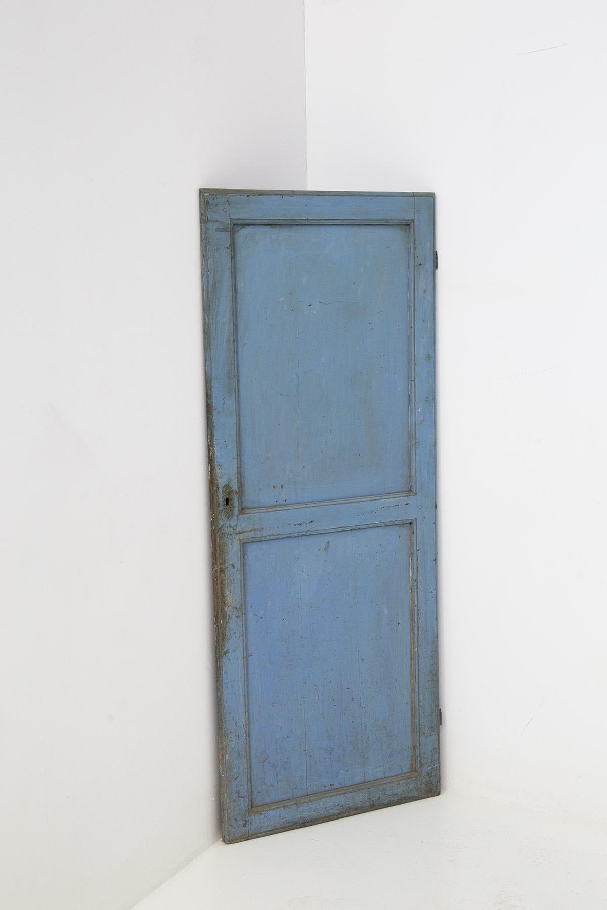 Puerta decorativa italiana de estilo fané de principios de los años veinte. La puerta es de madera pintada de azul. La puerta es evidentemente antigua y, a través de la intemperie, ha creado un envejecimiento decorativo perfecto. Se puede ver que el