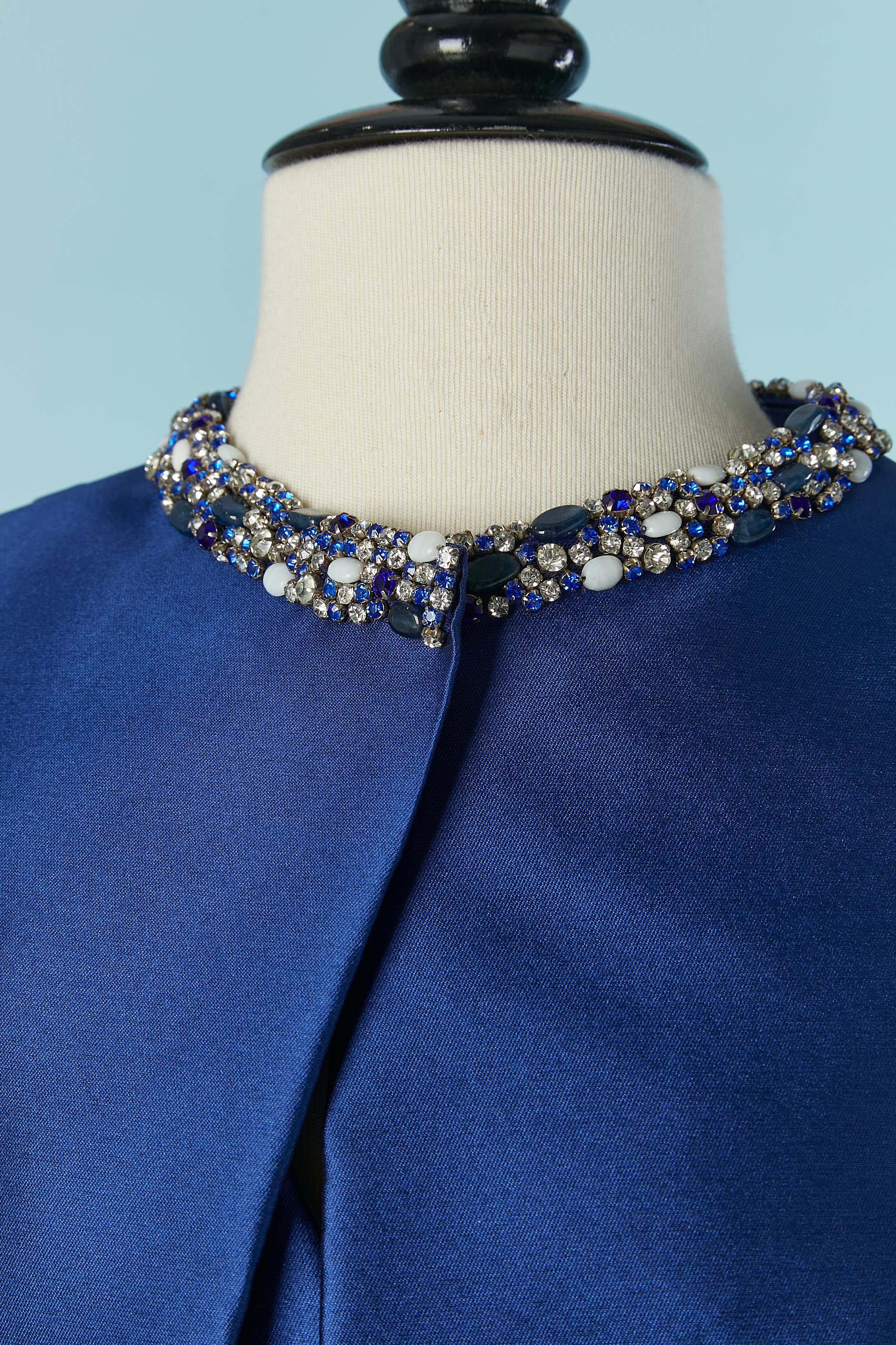 Blue jacket and asymmetrical cocktail dress ensemble with rhinestone embellishment. Main fabric composition: 15% silk, 85% polyester. Lining composition: 100% silk.
Hook&eye closure on the jacket on the top middle front. 
Top stitched bow ended with