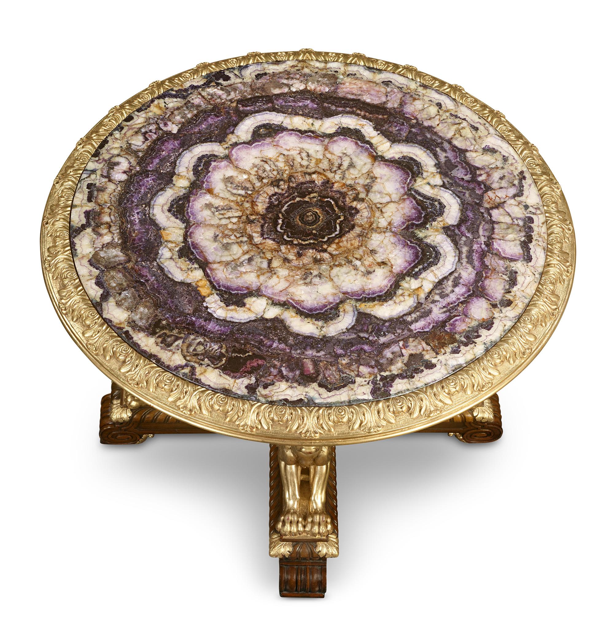 Blue John Table
Circa 1840

This extraordinary table is among the finest examples of rare Blue John plateaus in a single continuous slab. Elevated by a monumental mahogany base adorned with four majestic gilded-wood winged lions and intricate