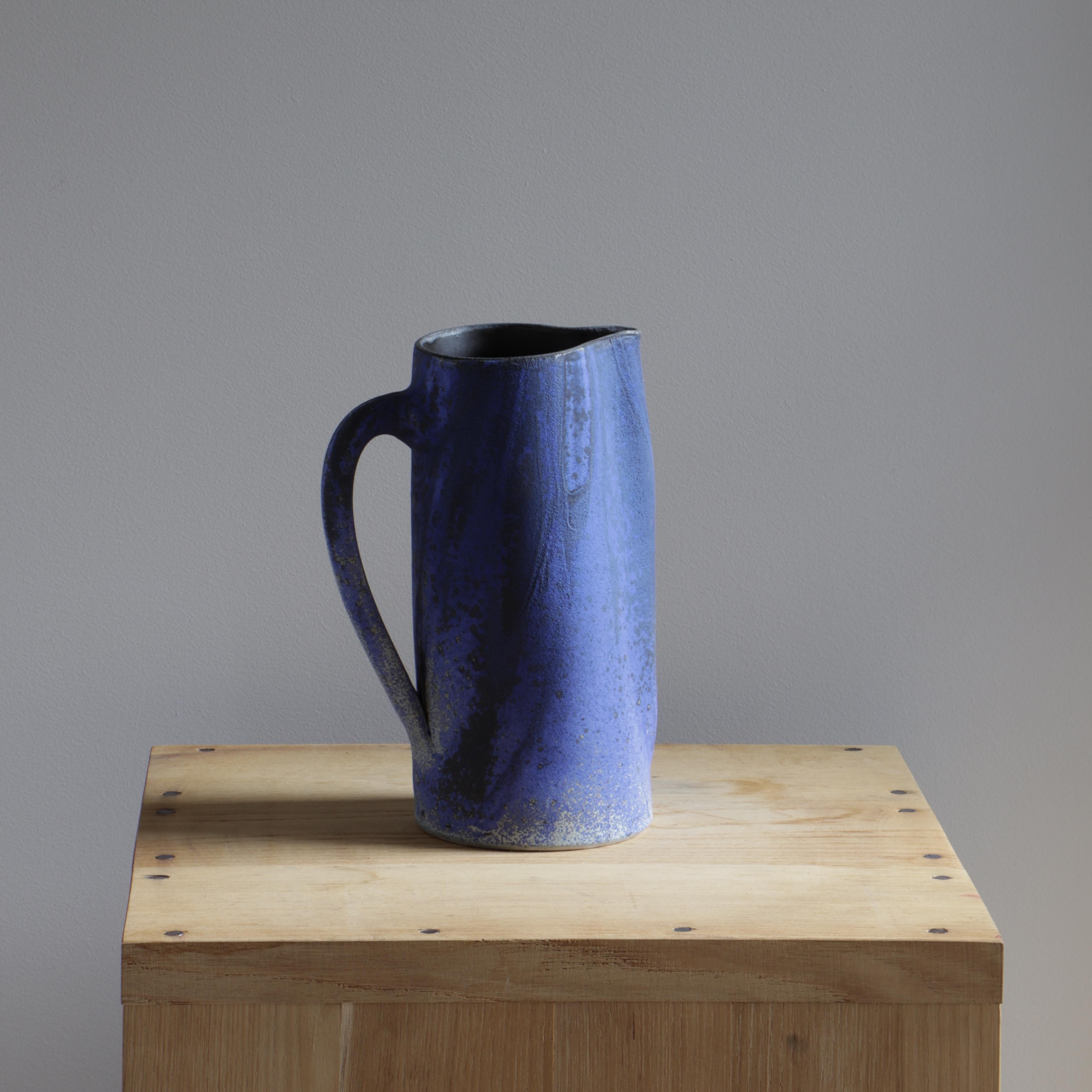 This ceramic jug was created by Ingrid Van Munster. Her works are made of porcelain sandstone. The colourisation phase consists in covering her pieces with enamel, after a first firing at 1000°C. She manufactures her own matt and satin enamels in a