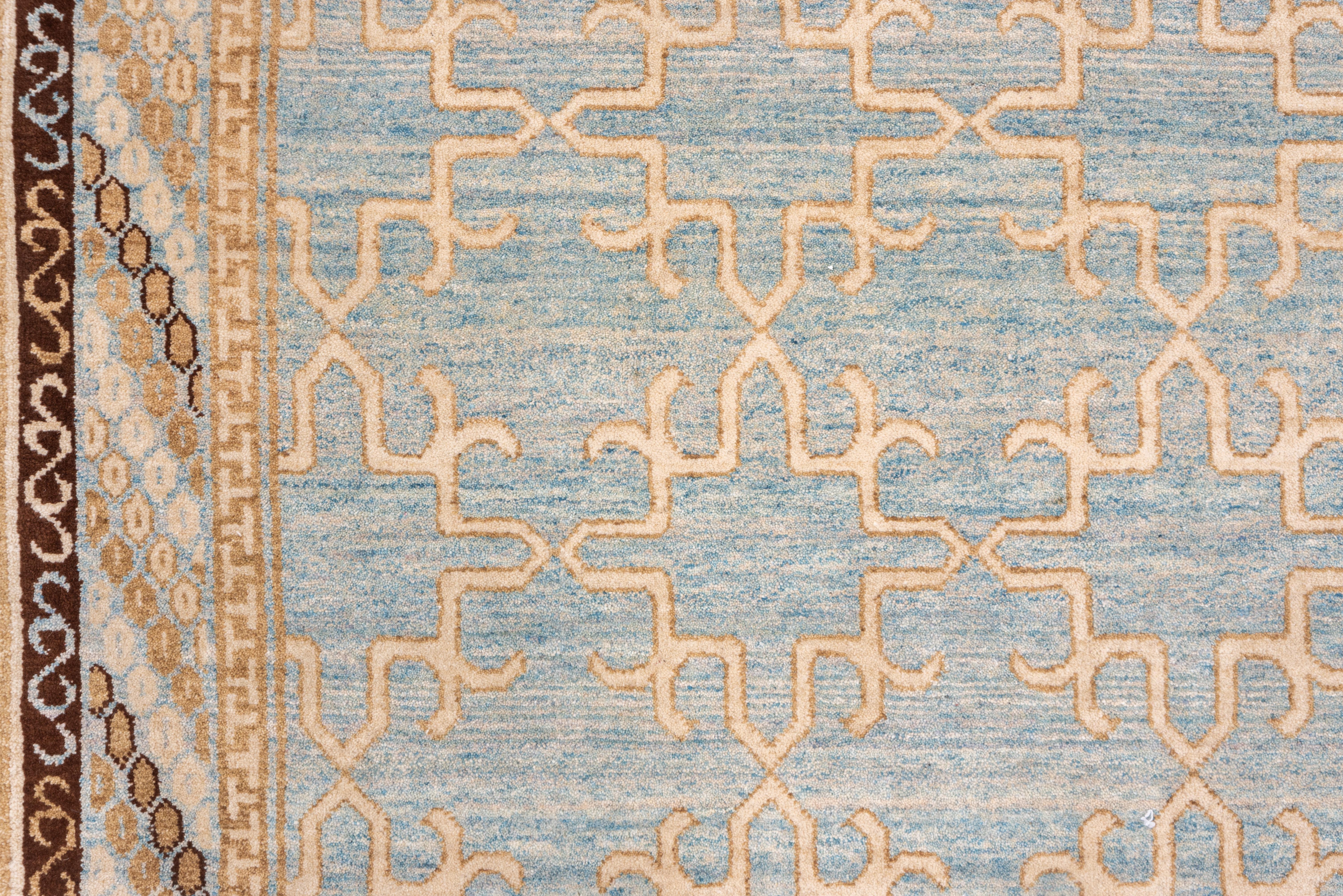 The abrashed soft blue ground features a multi-column pattern of outline squares with points on all four sides, within a narrow diagonally striped main border and lesser ones with connected S's and T-frets.