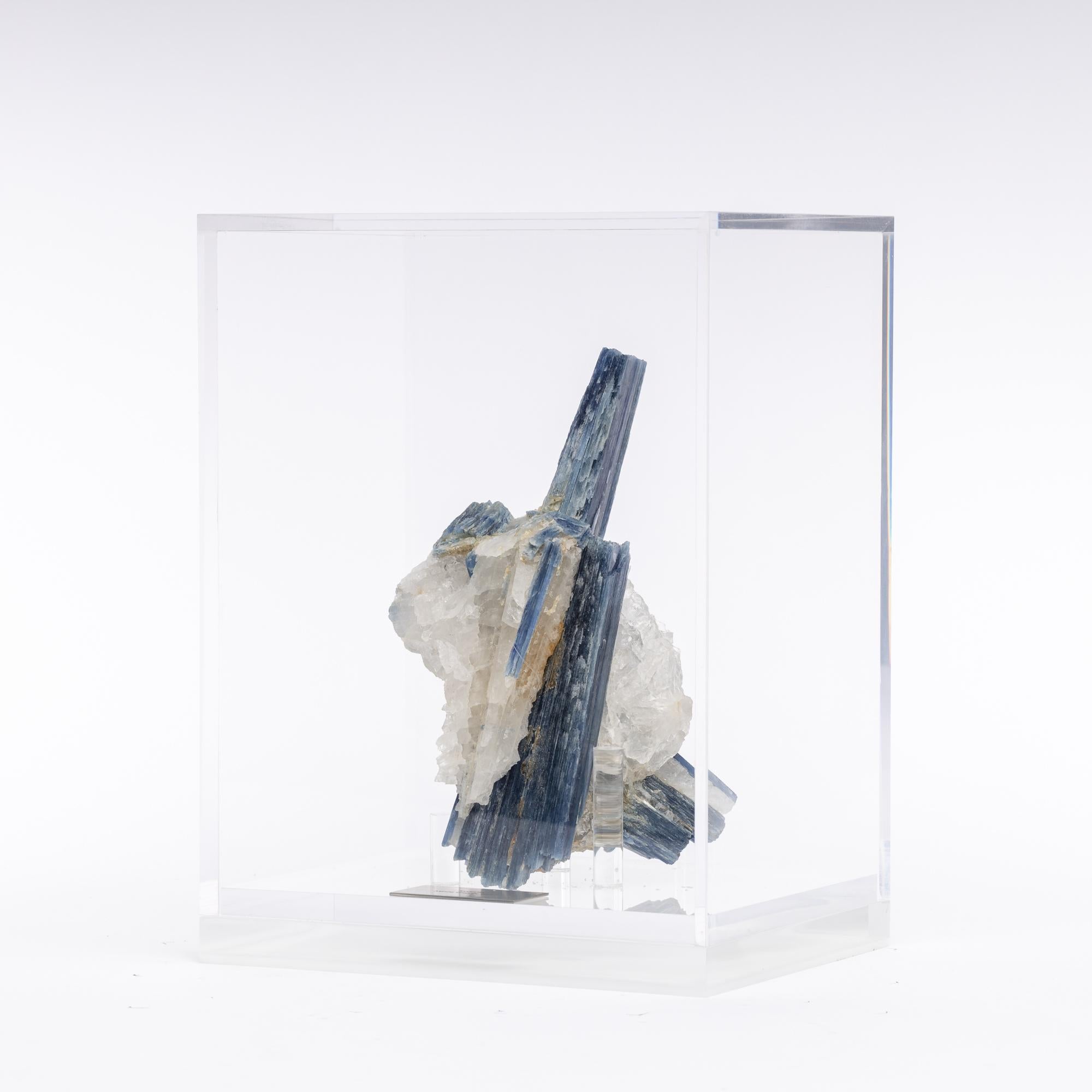 Blue kyanite and quartz specimen on acrylic box, natural crystal sculpture 

The name kyanite is derived from the ancient Greek word “Kyanos” that means blue.
The leyend says that a long time ago a storm overflow the Easter seas destroying