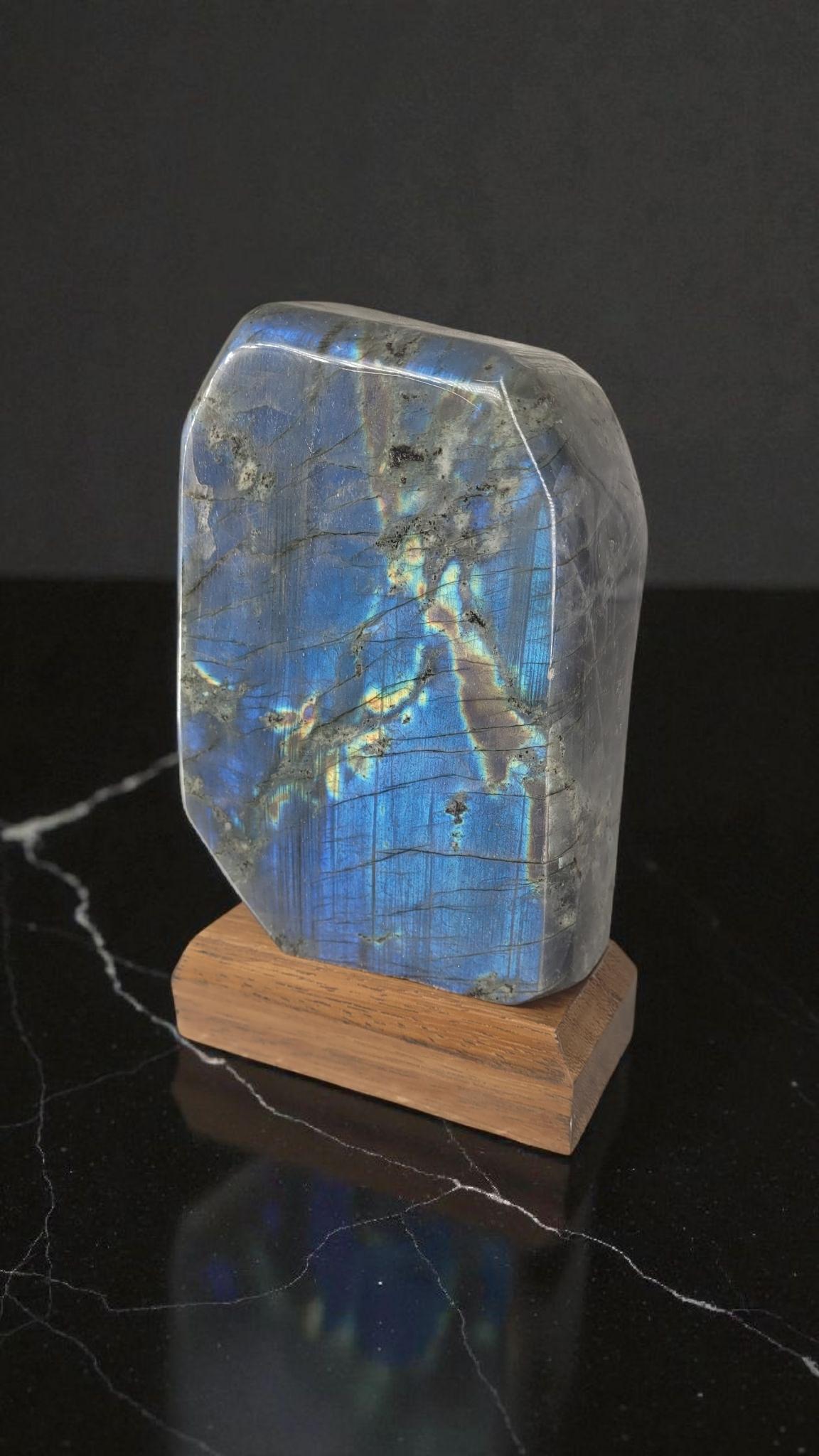 Proveniente dal Madagascar, questo estetico esemplare di gemma semipreziosa chiamata labradorite ha il peso e le dimensioni perfette per decorare una libreria o una scrivania. Pesa 1900 grammi e la base in legno lo sottolinea molto bene.