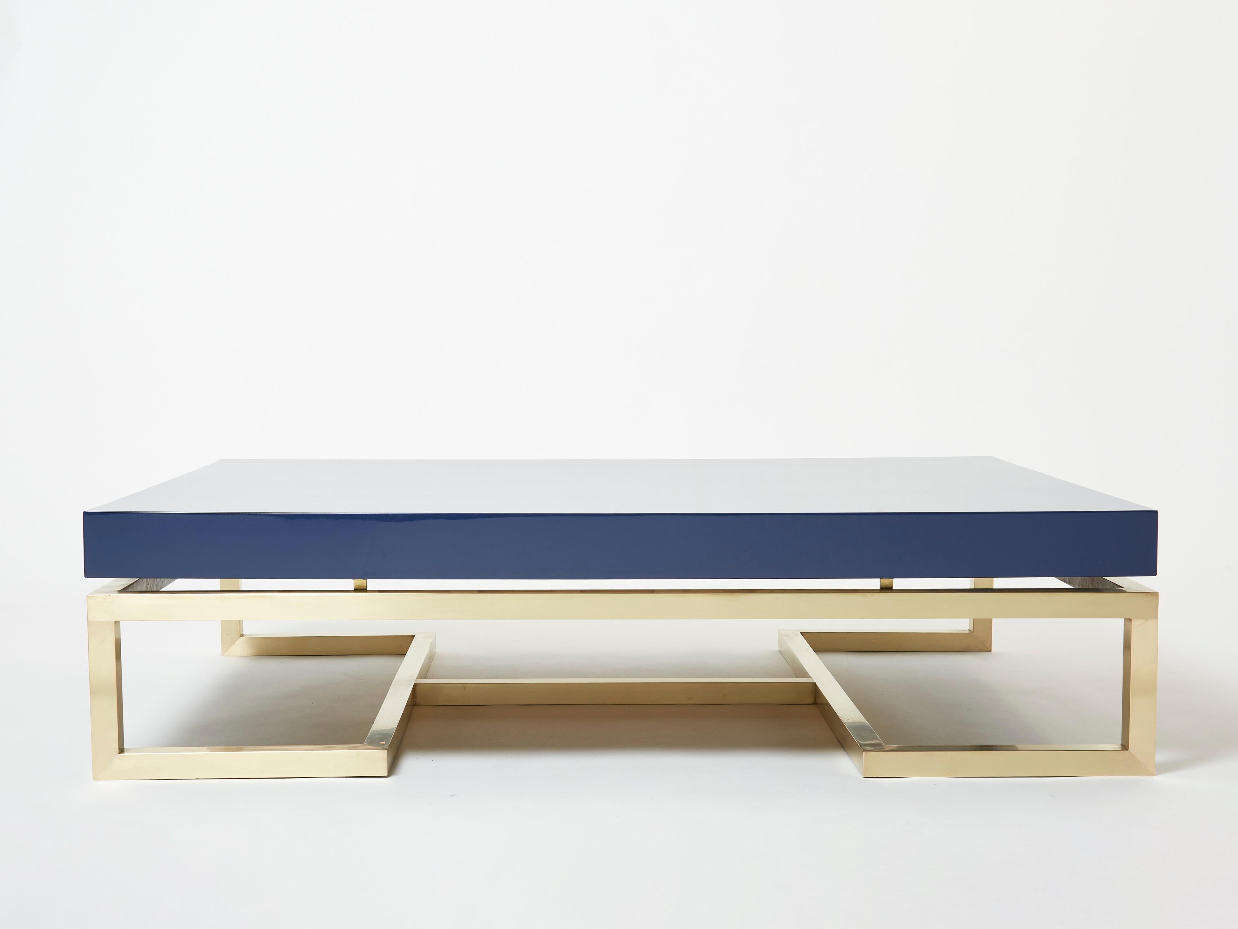 Designed by Guy Lefevre for Maison Jansen in the late 1970s, this beautiful coffee table features strong silky brass legs, with a dark ocean blue lacquered top. Its symmetry and strong architectural design combine to create a nice 1970s feel. It