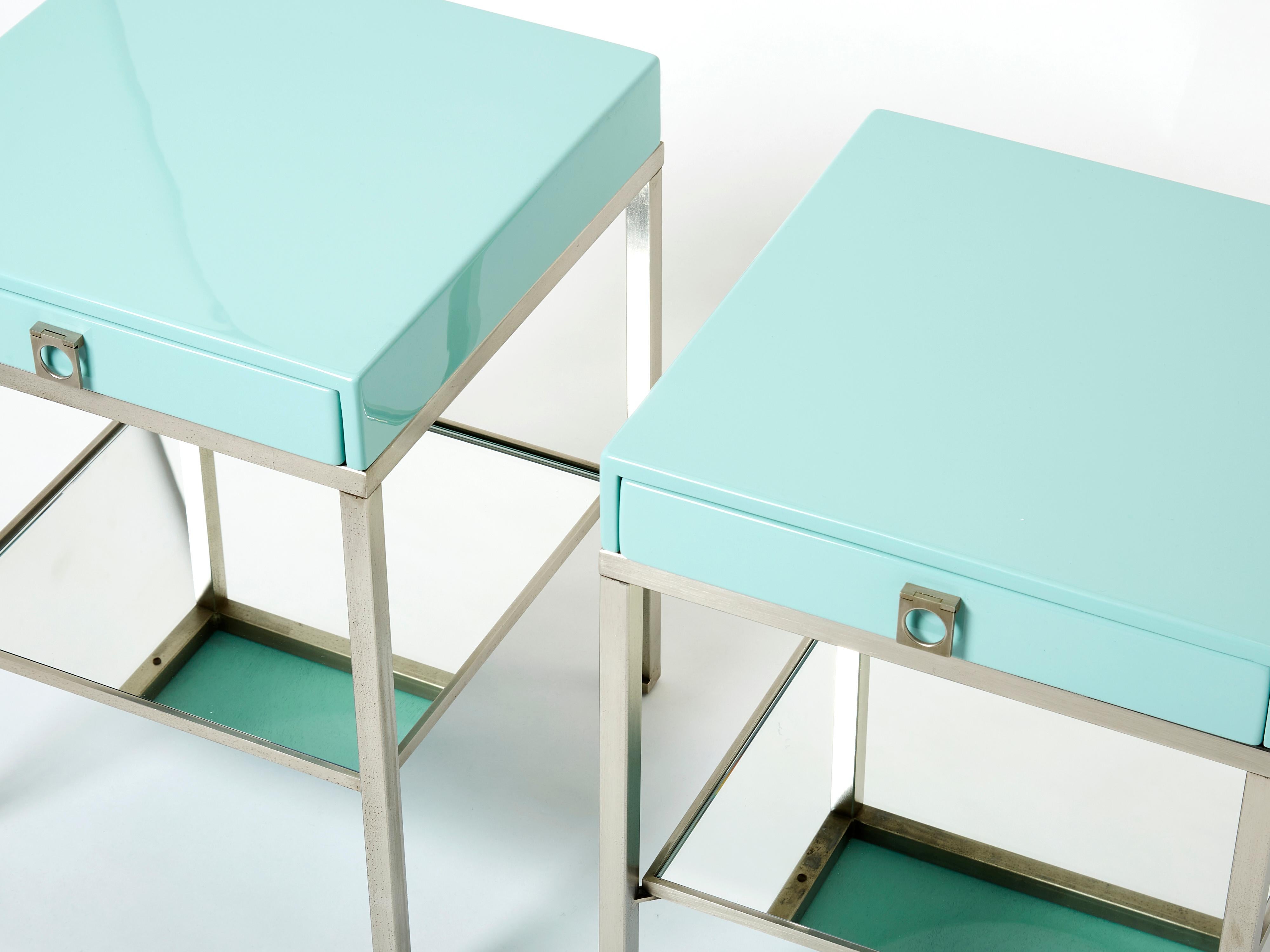 Simple lines point to these two-tier end tables french mid-century roots. Designed by Guy Lefevre for Maison Jansen, it features silky steel legs, with light blue lacquered top and drawer, with mirrored shelf under. Its symmetry and strong