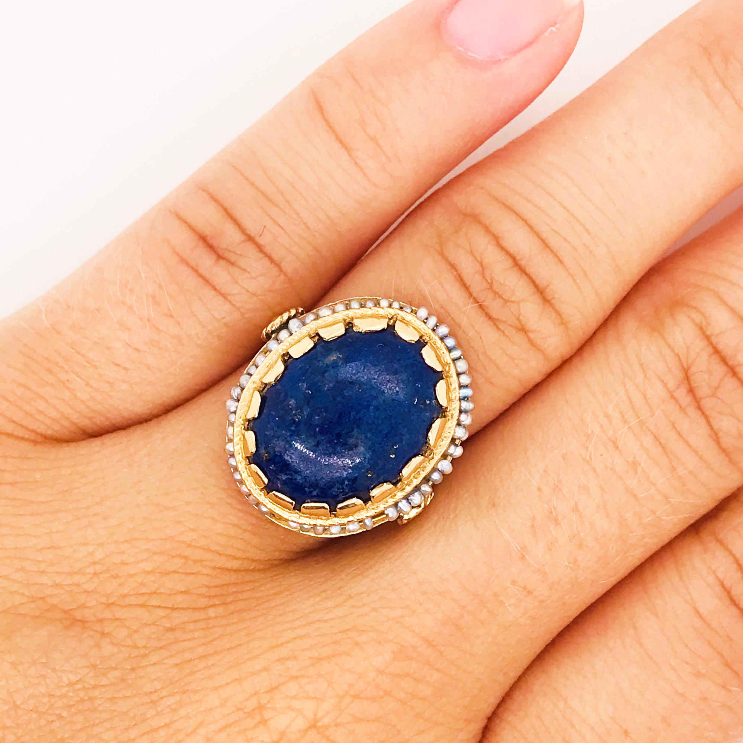 This Circa 1960 blue lapis and seed pearl ring is so interesting and eclectic. The blue lapis is 6 carats and oval in shape with a beautiful color with the natural gold veining in the gemstone.  The halo of seed pearls are all genuine, cultured