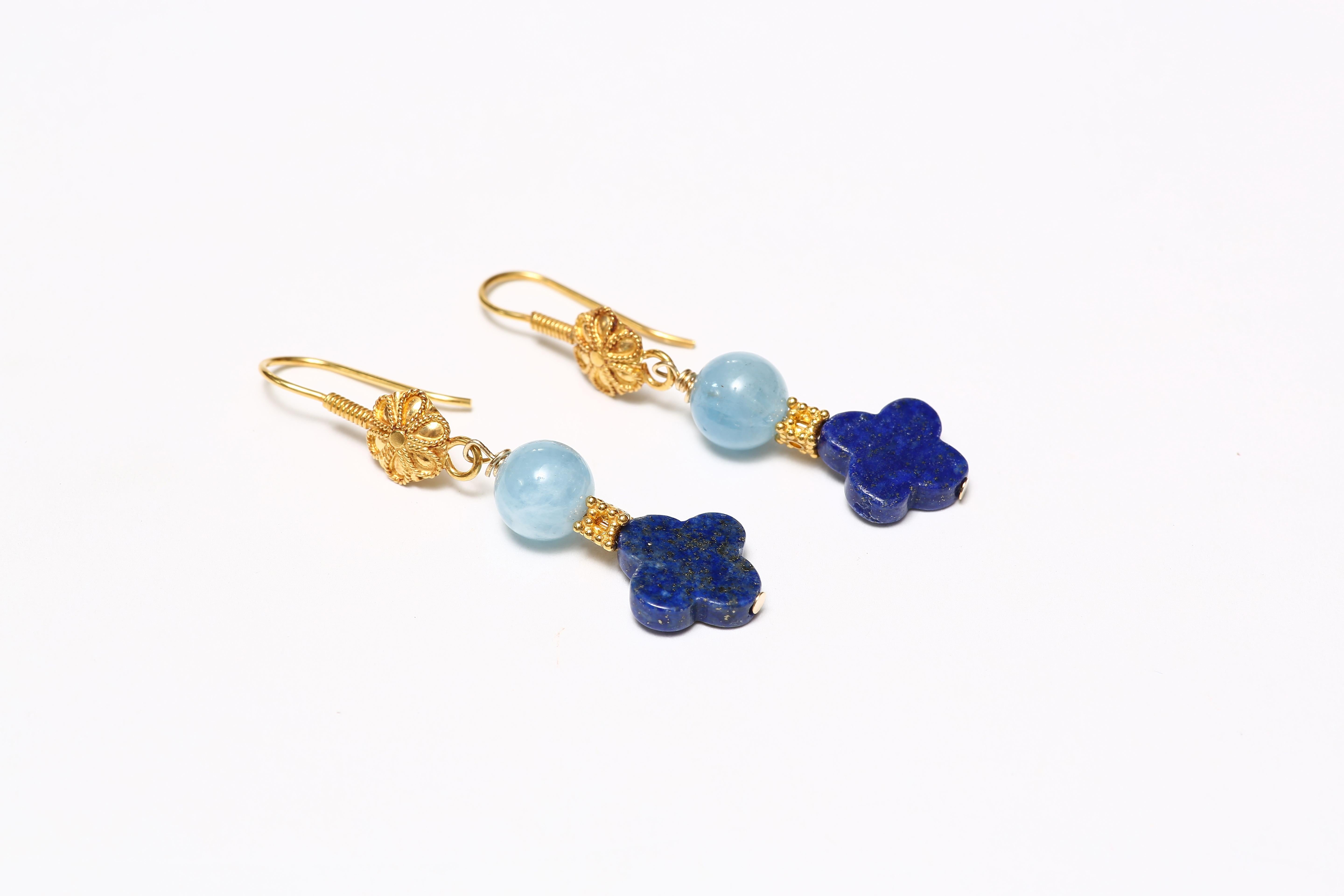 A charming pair of earrings handcrafted with solid 18K gold hooks with a flower front, with drops of an aquamarine bead and a quatrafoil vibrant blue lapiz bead, spaced by 18k solid gold faceted bead. 

Designed by AMANDA CLARK for Altfield, our