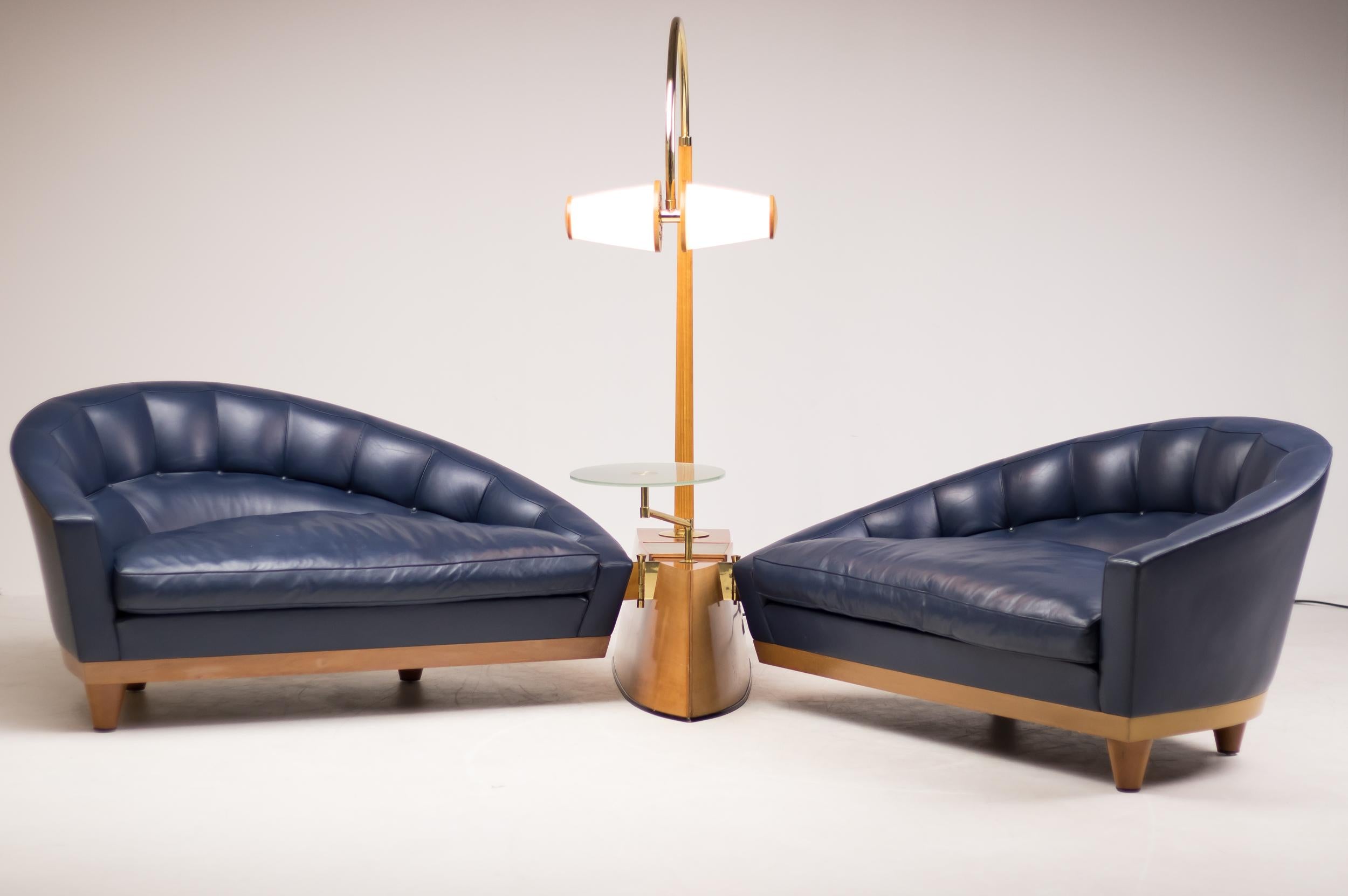 The centre of this piece is a heavy keel shaped base in solid cherrywood. The two blue leather sofas on solid cherry legs with concealed wheels are connected to the base by means of a polished brass hinge.
The base also supports a cherry and brass