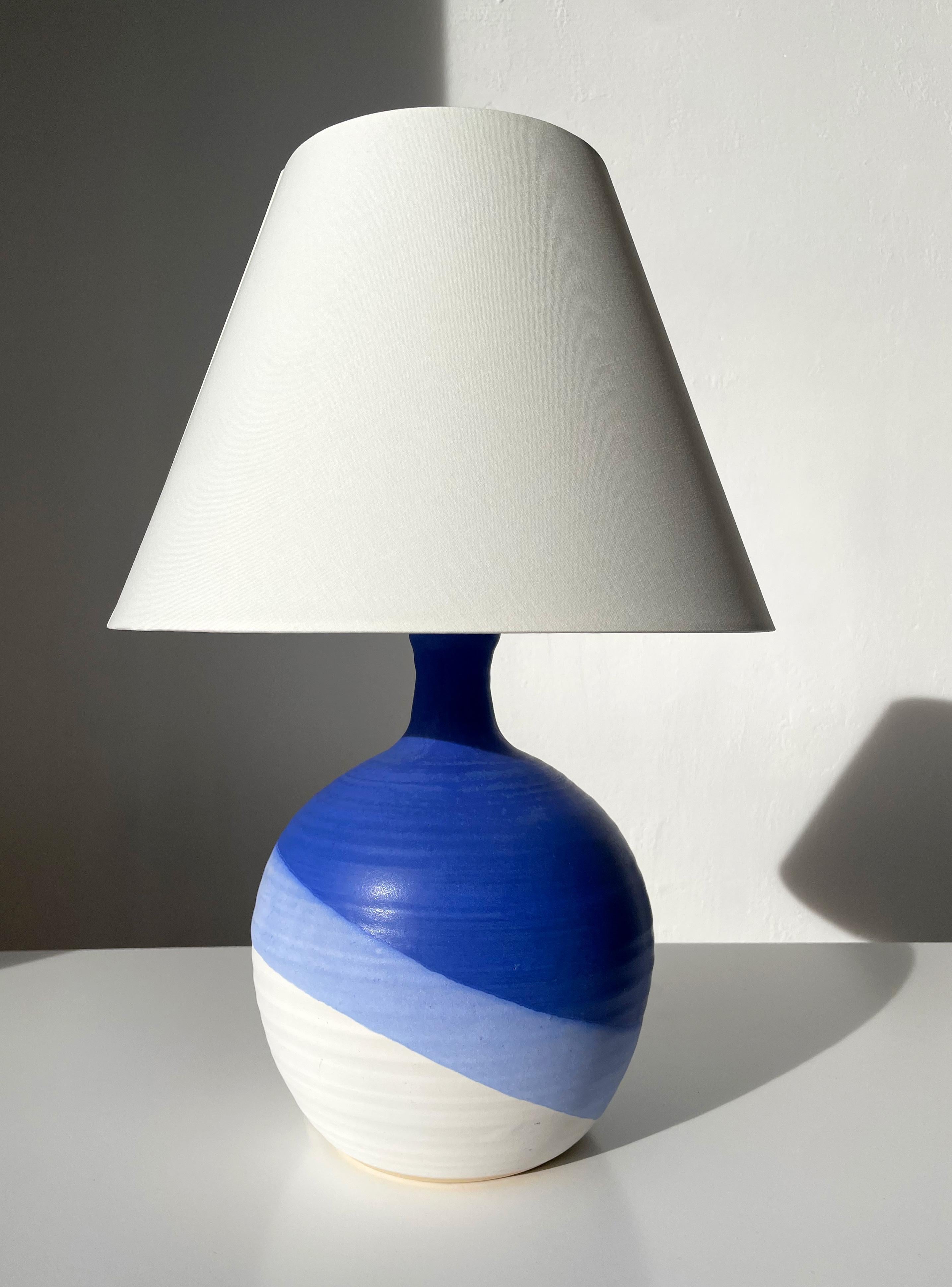 Lampe de table moderniste danoise en céramique en forme de globe. Glaçure bleue brillante sur glaçure lilas et blanche mate en bandes asymétriques accentuant la forme ronde. Fabriqué par KN Keramik dans les années 1980. Signé sous la base. Nouveau