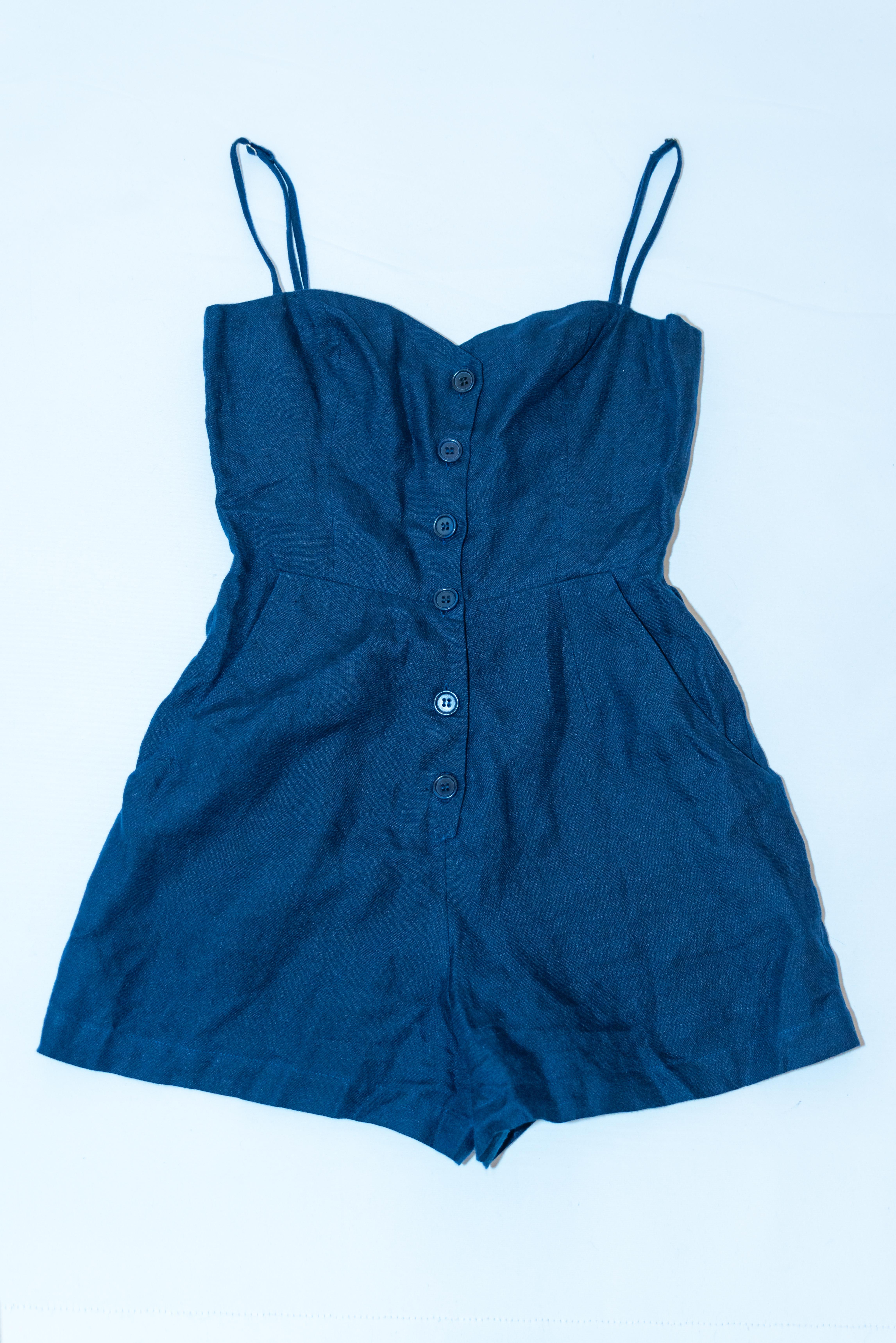 A fun playsuit for the summer weather  by Reformation. The suit has a button front opening, with a pocket on either side , spagetti straps. and is lined. Made in Italy.
Size 0 , Measurements: Bust 34'', Shoulder to hem 29'' , inside leg 3''.