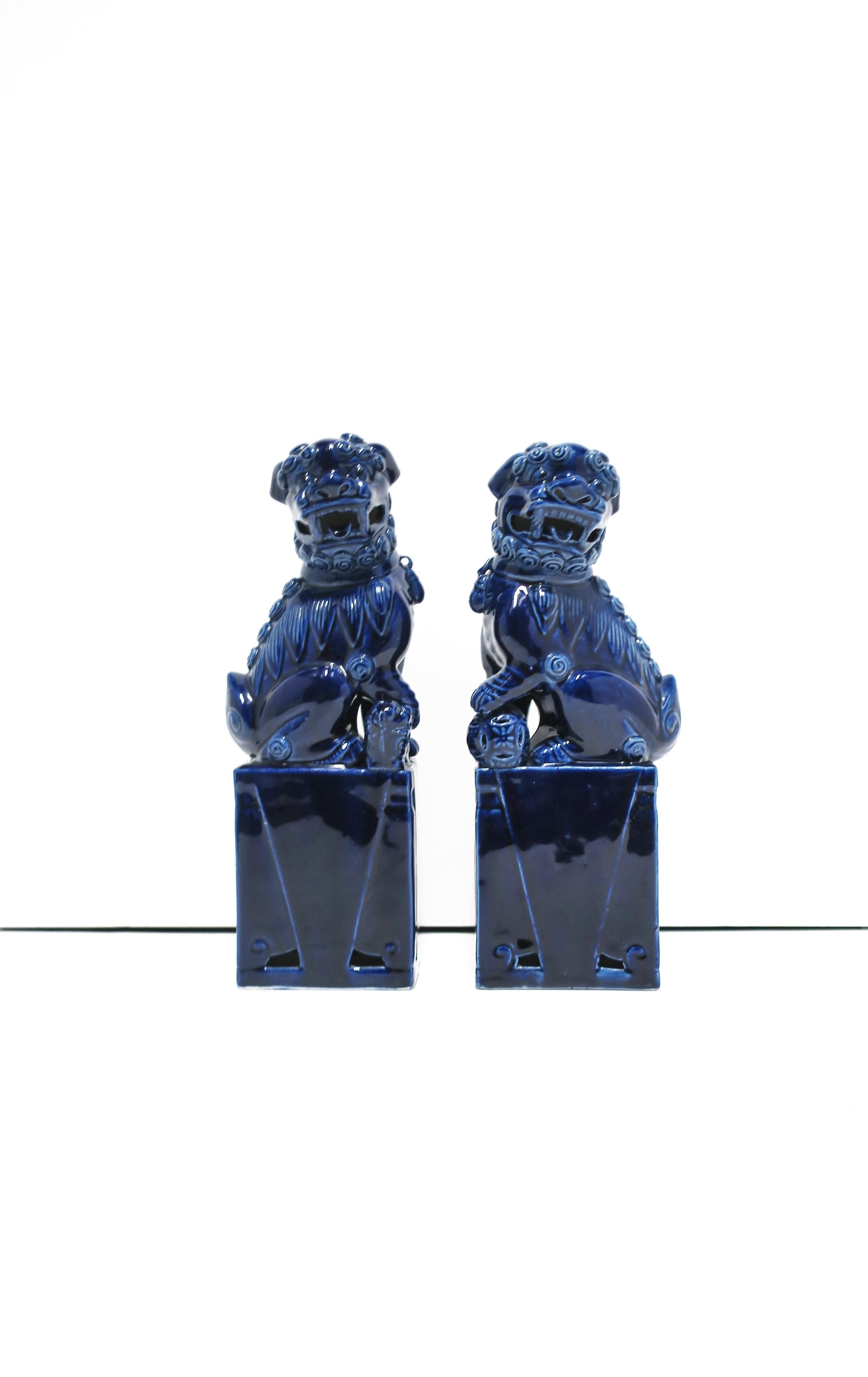 A beautiful pair of relatively tall dark blue or 'ink' blue ceramic Lion Foo dogs' decorative objects or bookends, circa late-20th century, English rule Hong Kong. Dimensions: 9.75