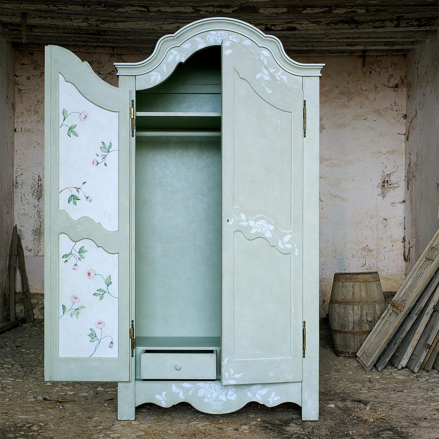 Introducing the Mantegna Armoire, a stunning piece that combines style and functionality. Hand-painted in blue with textural white flowers on the edges, it features contrasting white interiors adorned with colorful flowers. Inspired by the attention