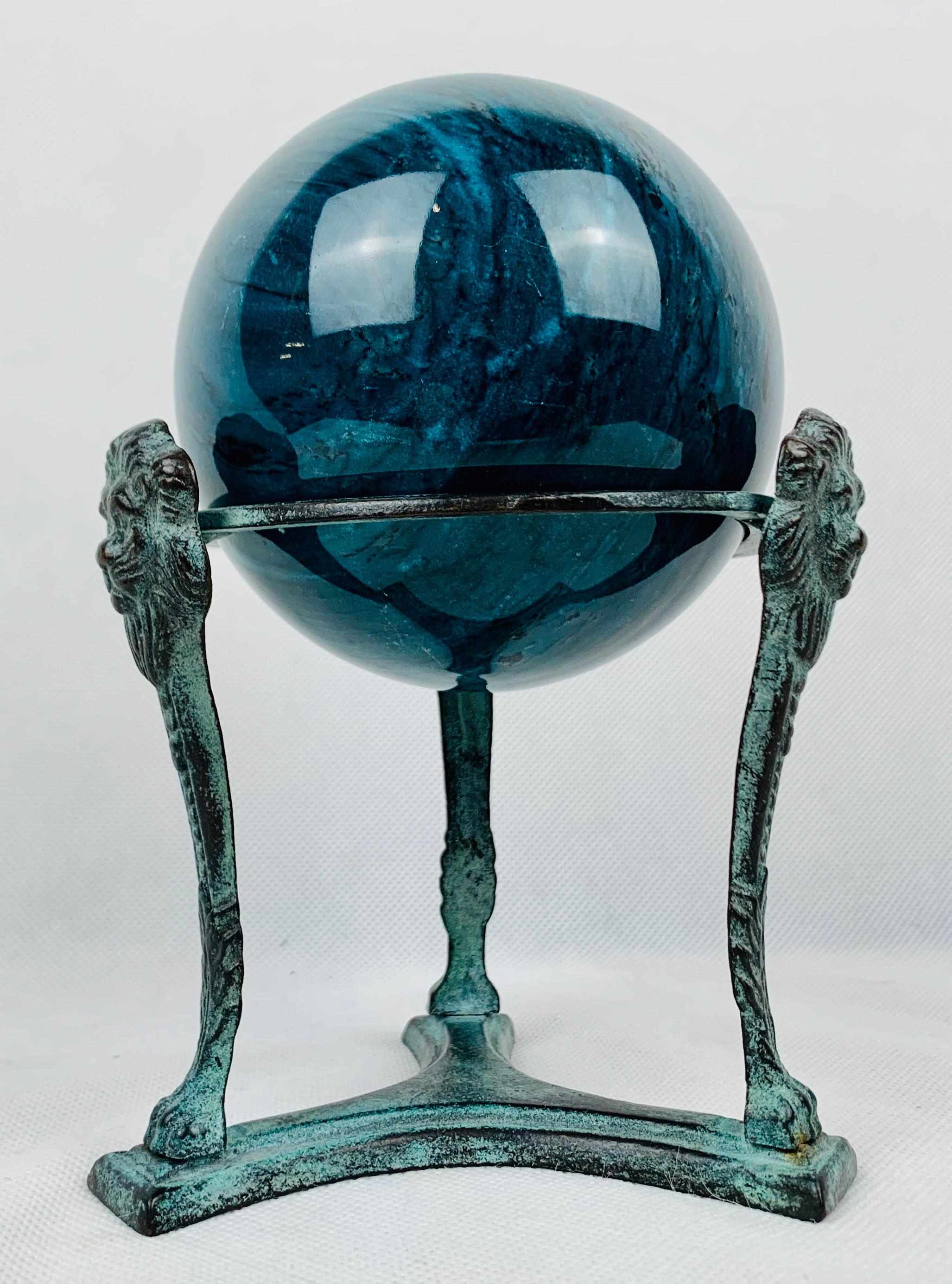 A handsome blue marble orb or sphere resting on a neo-classical stand. The tripod stand has a patinated finish with lion's faces and paws at the base.
If neo-classical objects appeal to you this piece would look great on any table, desk or shelf.