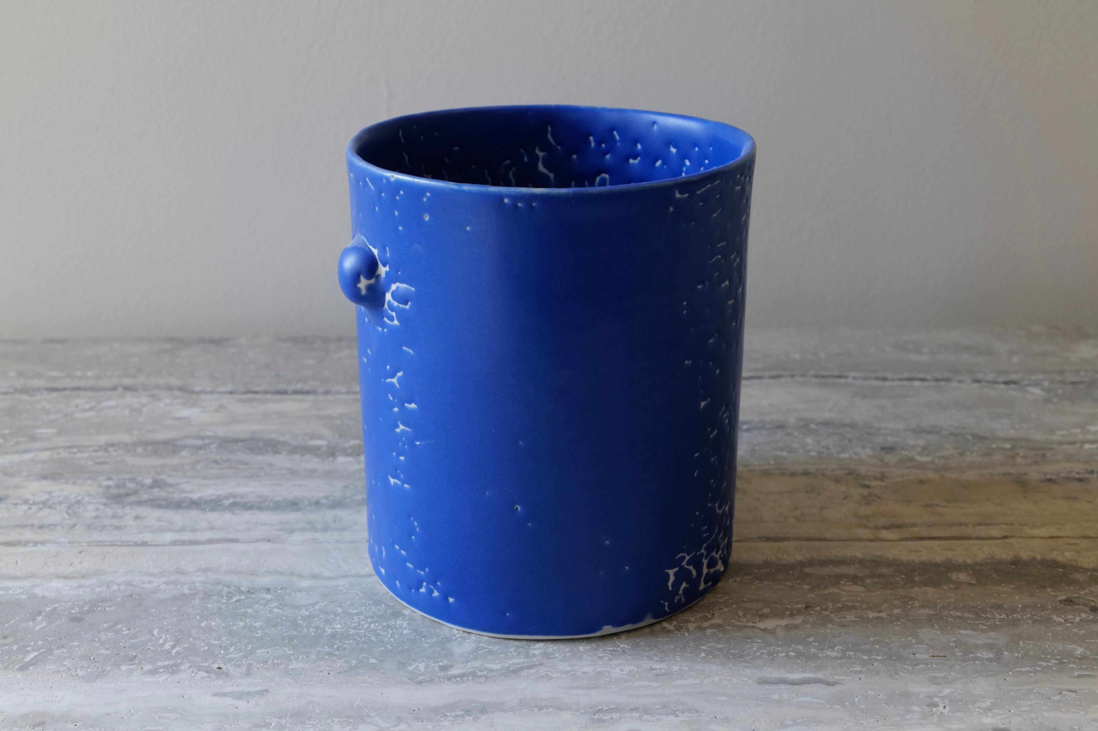 This vase is hand-cast in porcelain and glazed with a rich cobalt glaze that has a beautiful and loose crawl texture across the vessel. The ‘bumps’ motif recalls some classical embellishment with some loose evocation of the Baroque in an abstracted