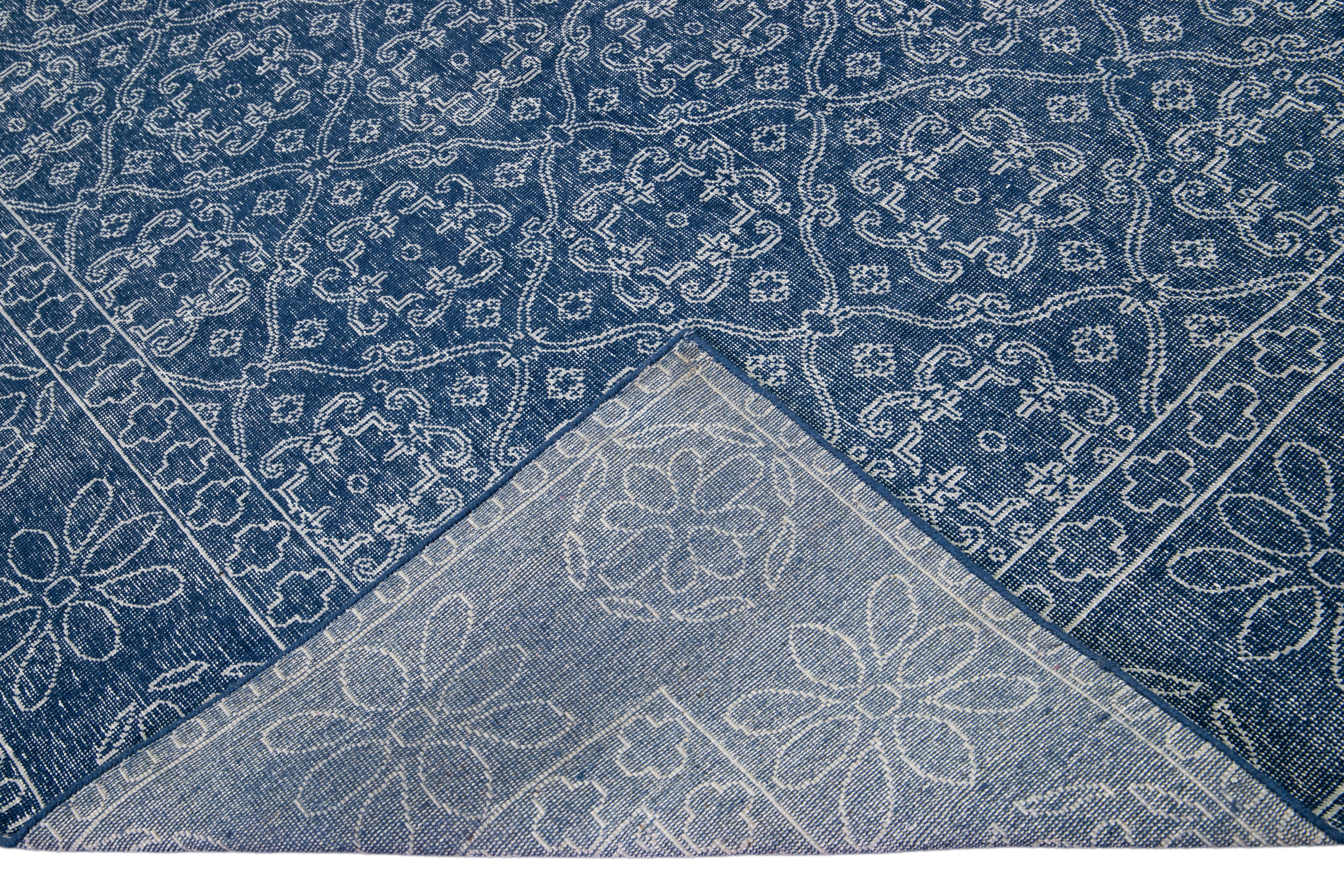 Schöner türkischer handgefertigter Wollteppich mit einem blauen Feld im Distress-Look. Dieser moderne Teppich hat weiße Akzente und ein wunderschönes, florales Spaliermuster.

Dieser Teppich misst: 9' x 12'.

Unsere Teppiche werden vor dem