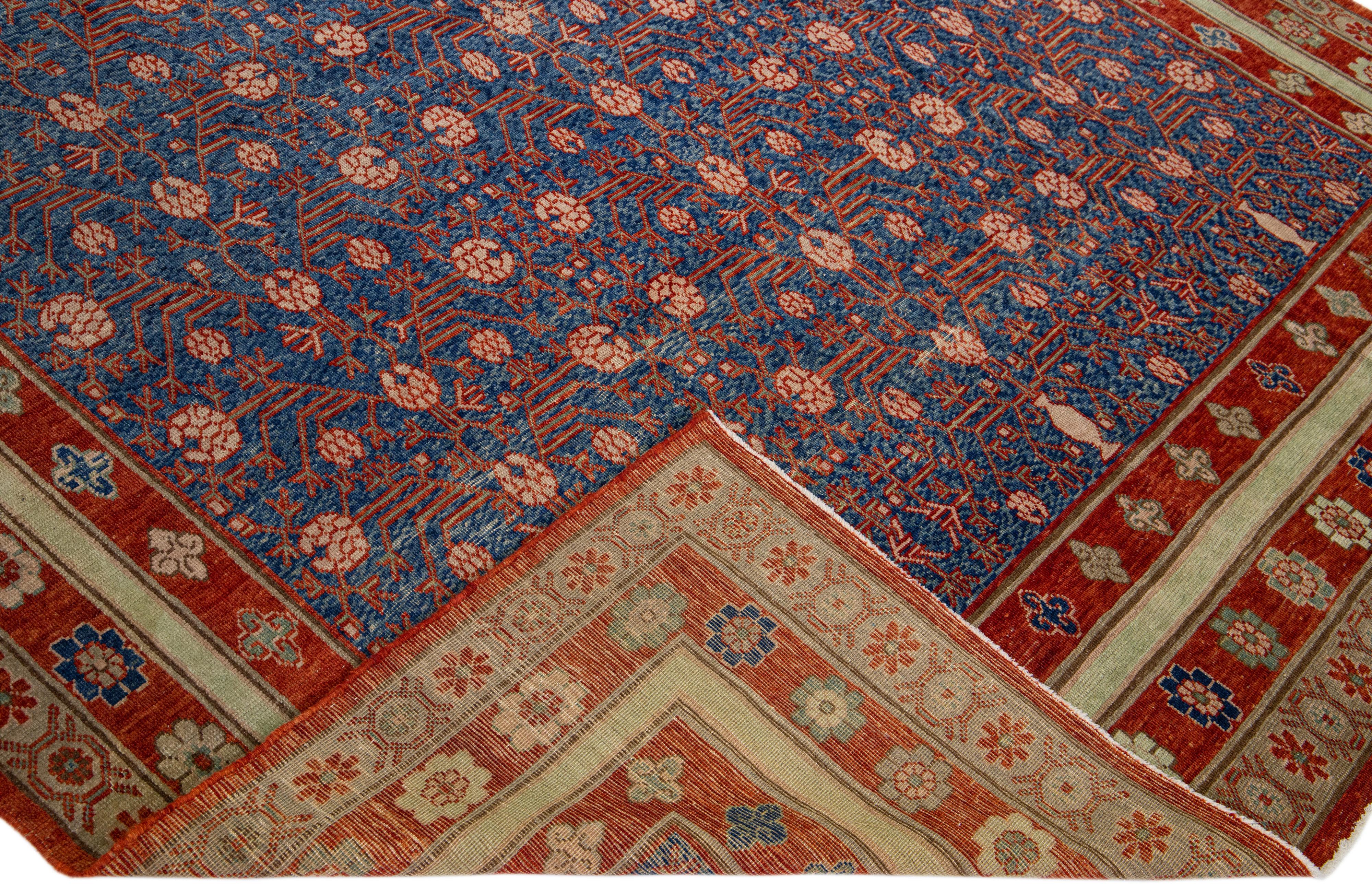 Beautiful vintage Khotan style rug with a blue field. This rug has a floral-designed red frame with multicolor accents in interconnected pomegranates rosettes, leaves, and vines design. 

This rug measures 7'8