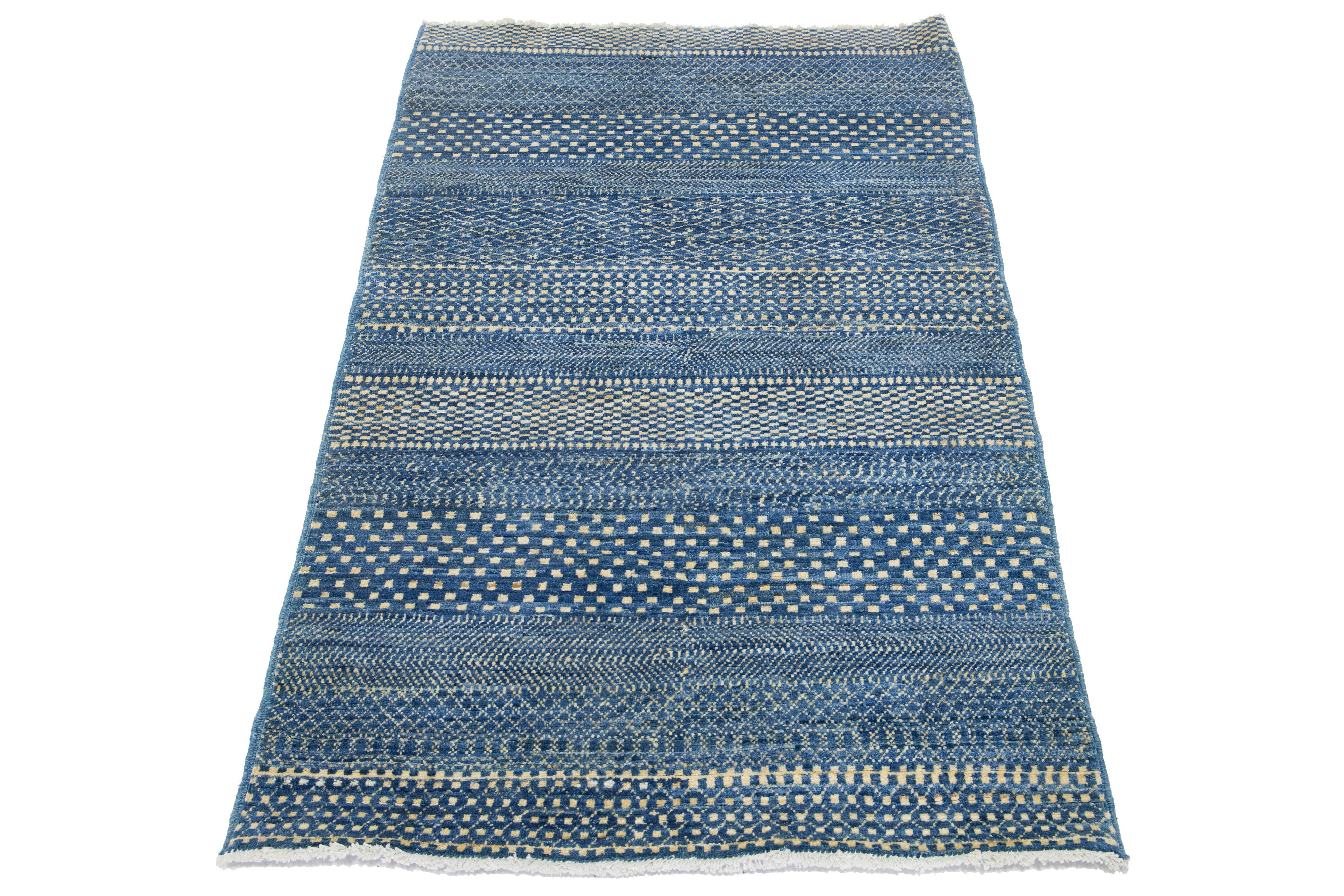 This handcrafted wool rug, designed in Afghanistan, showcases a geometric pattern accentuated by ivory color against a vibrant blue background.

This rug measures 3'2