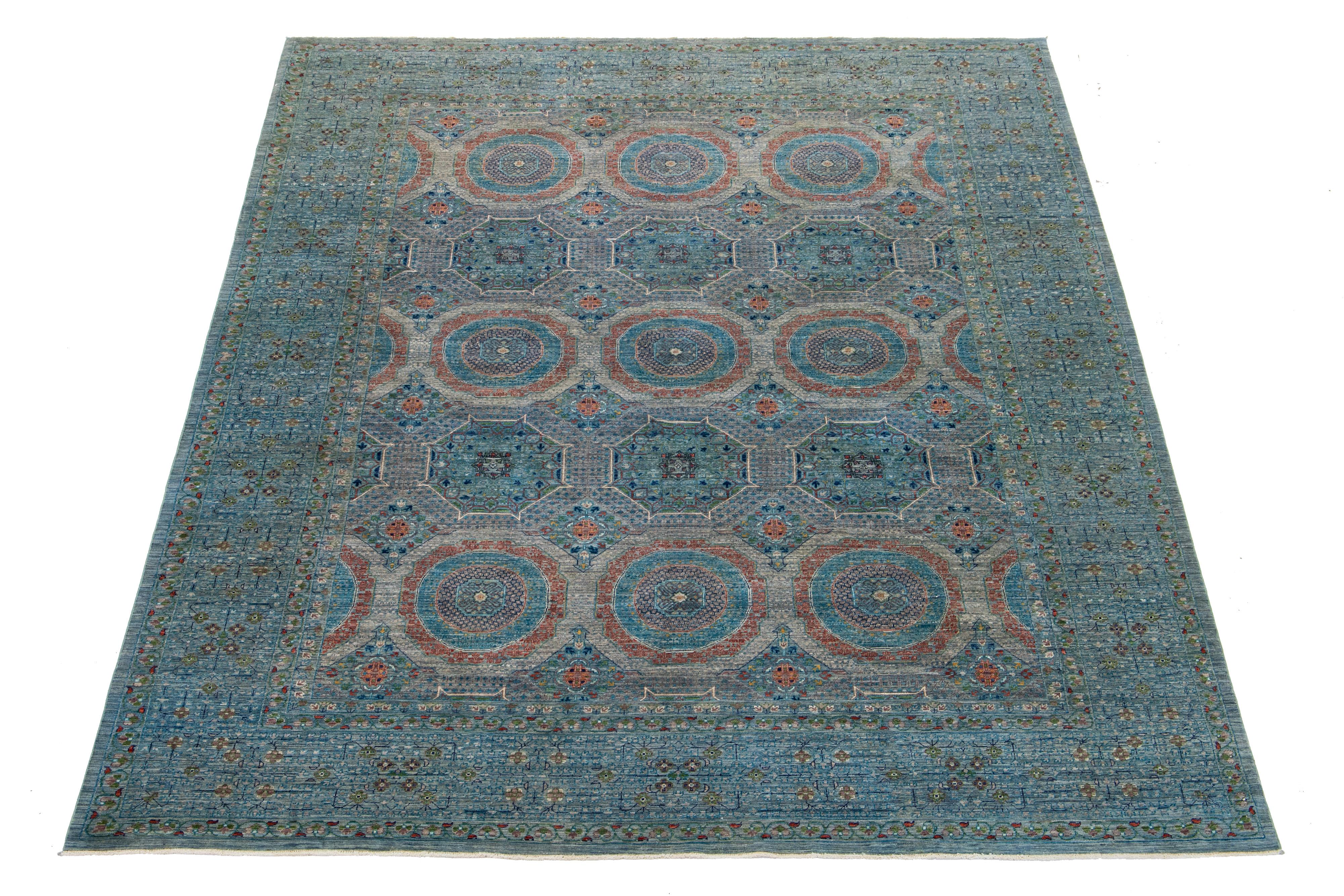 Questo tappeto in lana Mamluke ha uno sfondo grigio impreziosito da una serie di motivi geometrici multicolore. Annodato a mano e dal design contemporaneo, mette in risalto gli accenti blu.

Questo tappeto misura 9'1