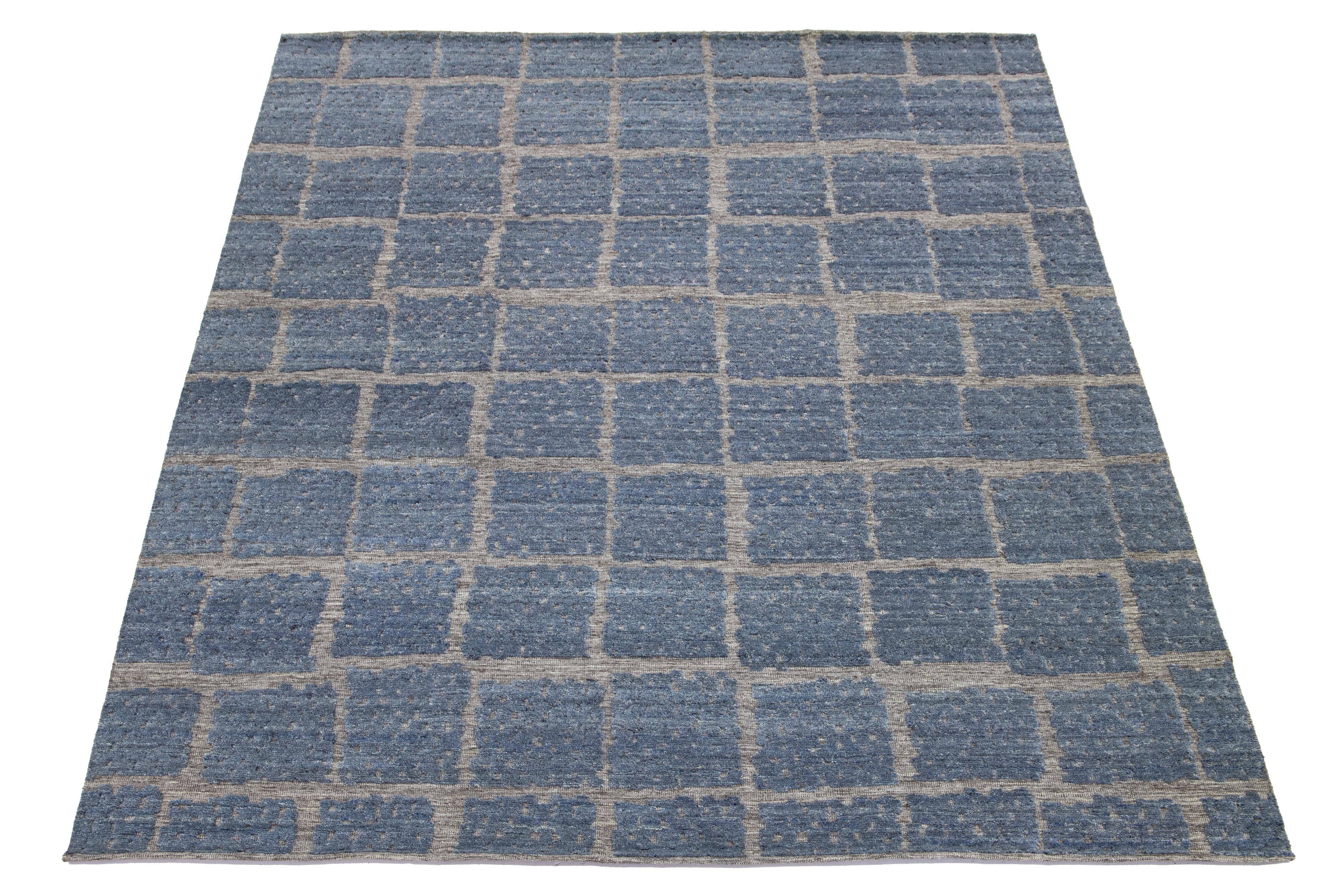 Dieser atemberaubende, zeitgenössische, handgeknüpfte Wollteppich im marokkanischen Stil besticht durch sein abstraktes Design in Grau und Blau, das jedem Raum Eleganz und Wärme verleiht und das perfekte Herzstück darstellt.

Dieser Teppich misst