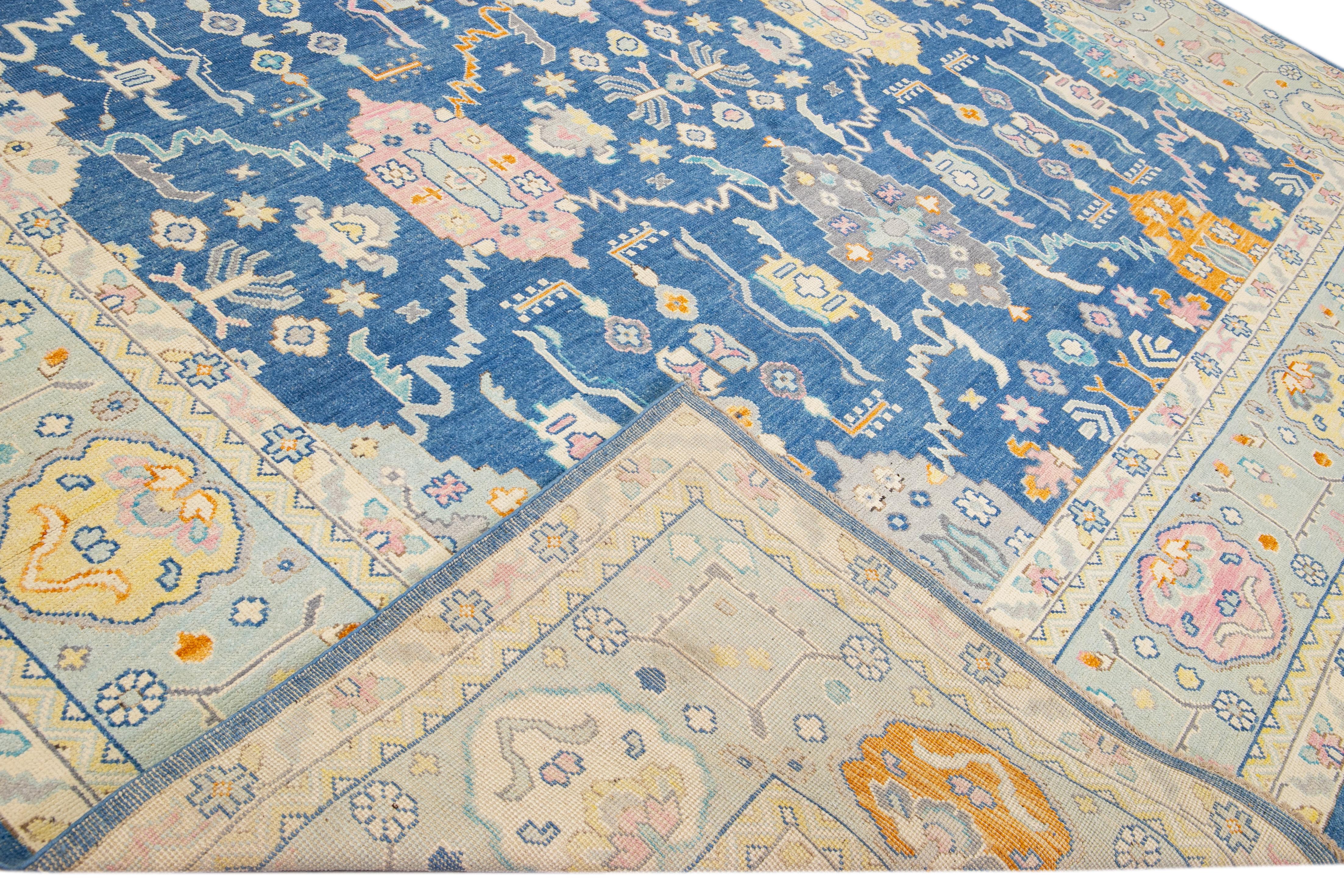 Magnifique tapis moderne Oushak en laine nouée à la main avec un champ bleu marine. Ce tapis Oushak présente des accents multicolores et un magnifique motif floral géométrique. 

Ce tapis mesure : 12'9