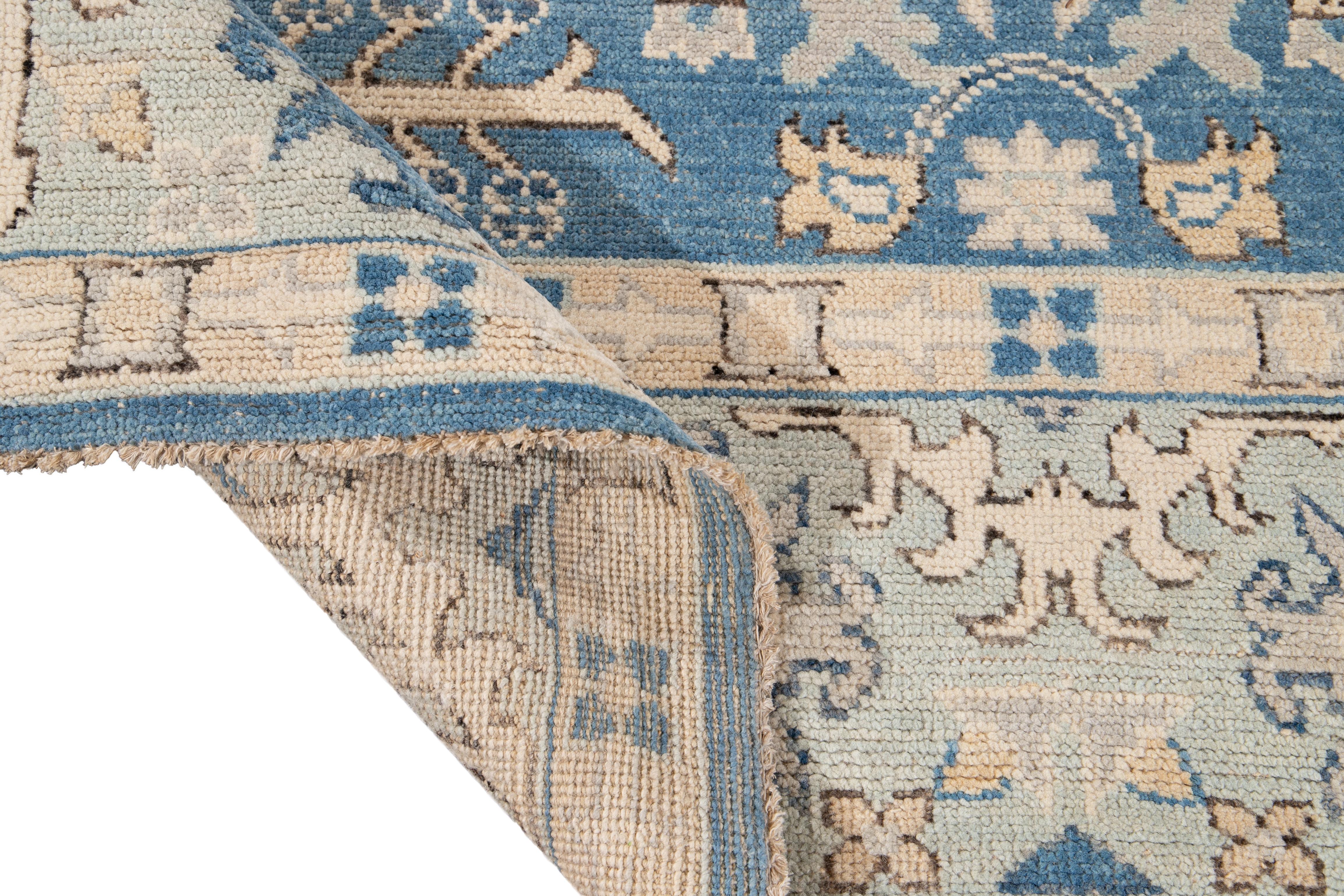 Beautiful contemporary Oushak Design hand knotted wool rug with a botanical floral design on a blue field and ivory accents throughout the piece. 

This rug measures: 9'4