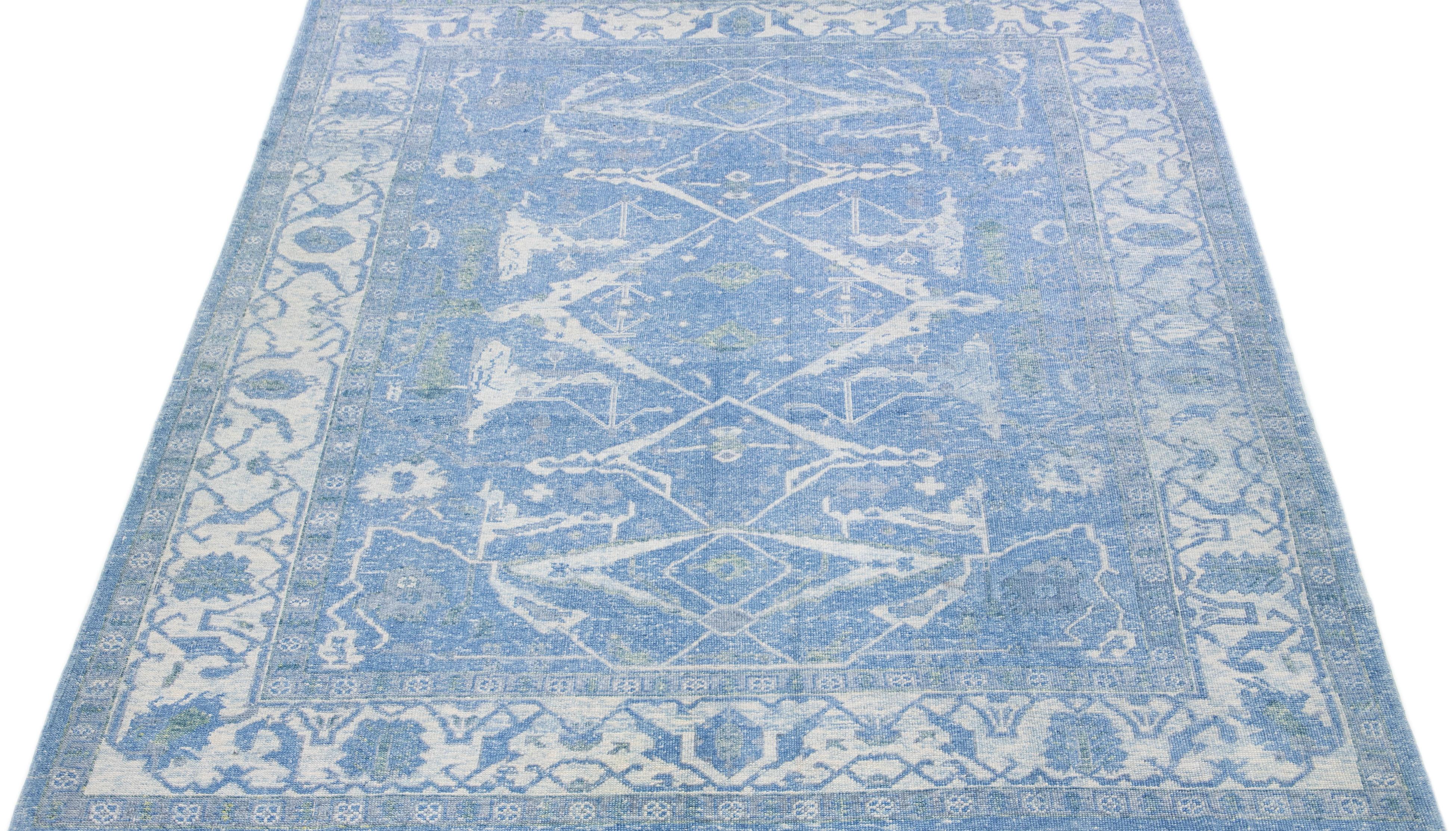 Beautiful modern Oushak hand-knotted wool rug with a blue color field. This Turkish Piece has white and green accent colors in a gorgeous all-over floral design.

This rug measures: 10'1