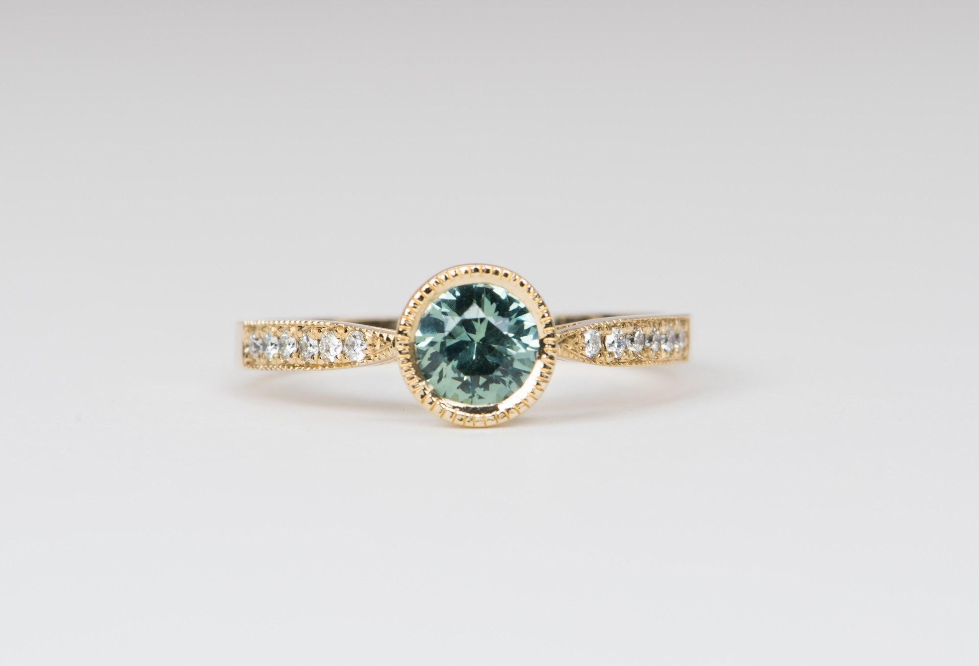 ♥ Massiver Ring aus 14 Karat Gelbgold:: besetzt mit einem runden Montana-Saphir in einer gefrästen Lünette:: flankiert von graduell großen Diamanten auf dem Band und gesäumt von zierlichen gefrästen Ringen für zusätzliches Interesse
♥ Die gesamte